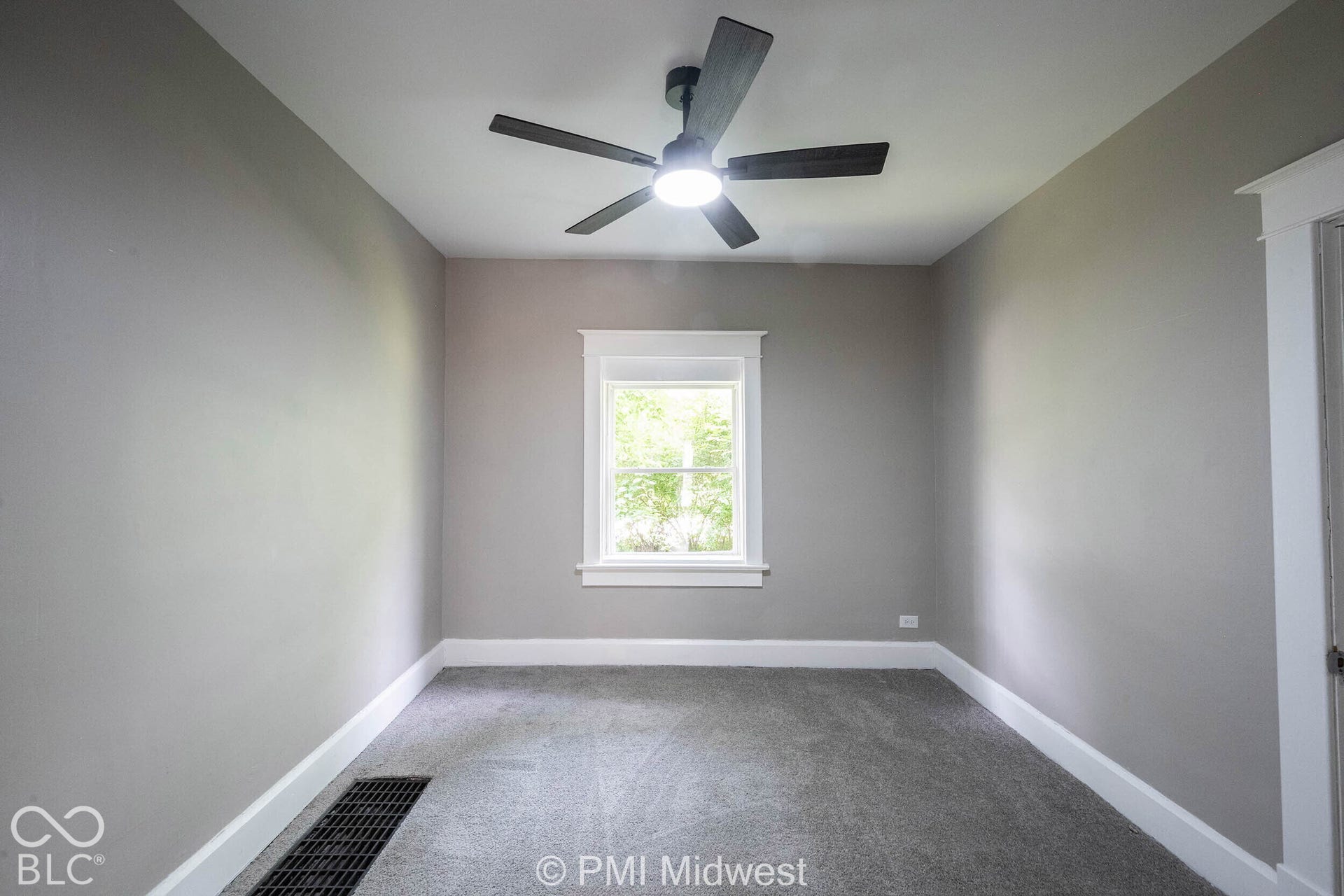 Recessed window with white trim, gray textured carpet, neutral wall paint, and a dark-bladed ceiling fan with integrated lighting