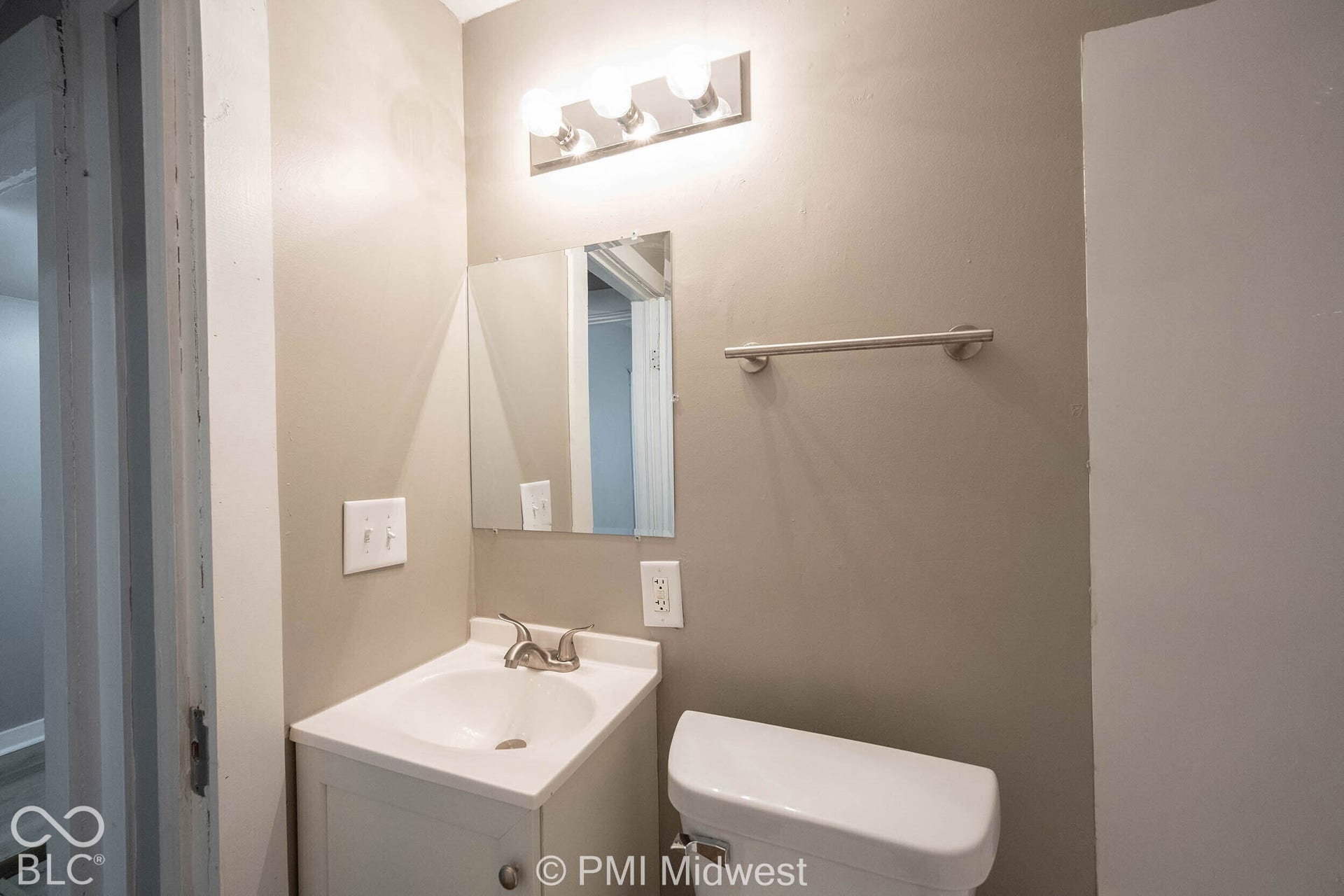Vanity with integrated sink, brushed nickel faucet, wall-mounted mirror, and overhead light fixture