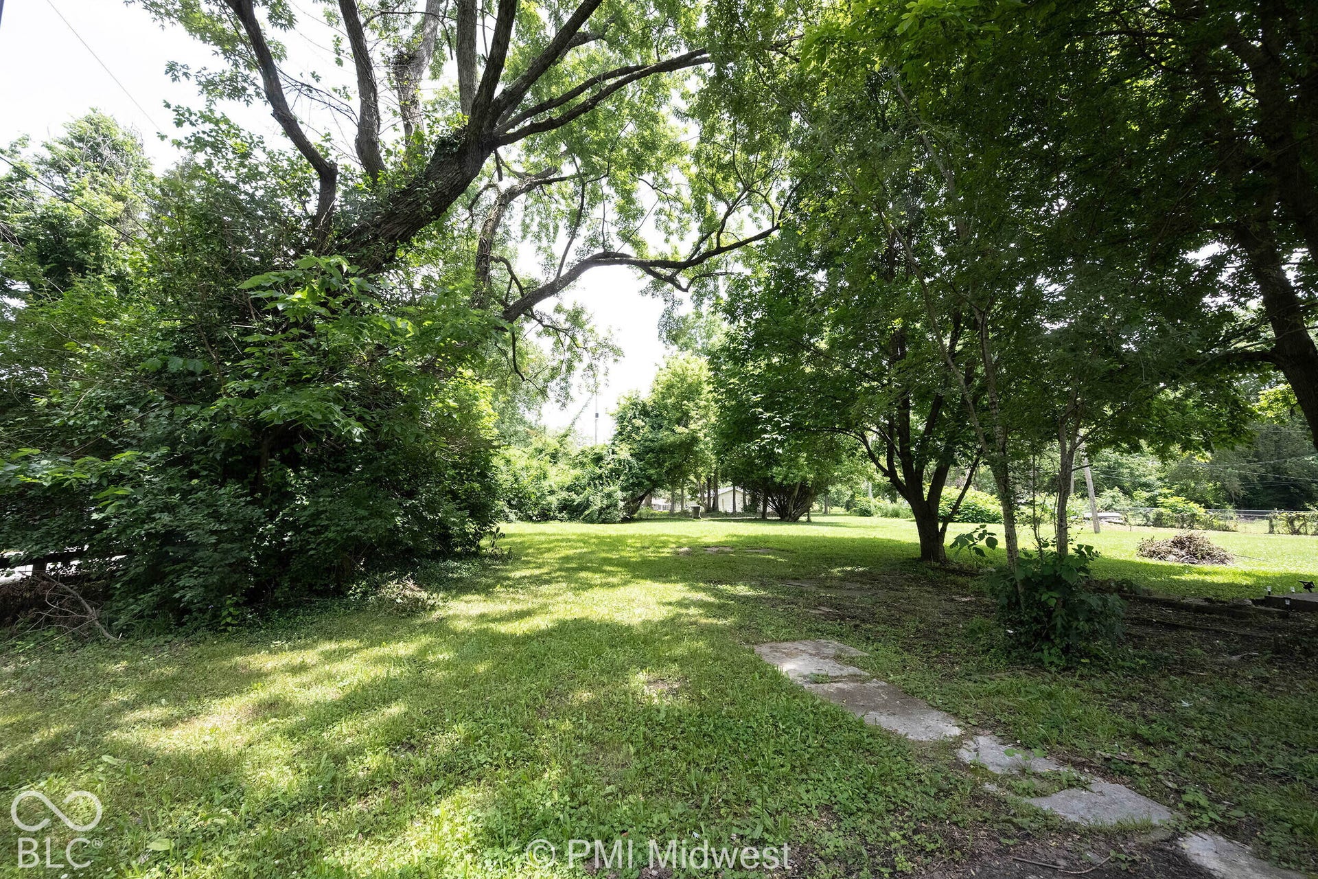 Expansive green space featuring a grass lawn and mature trees