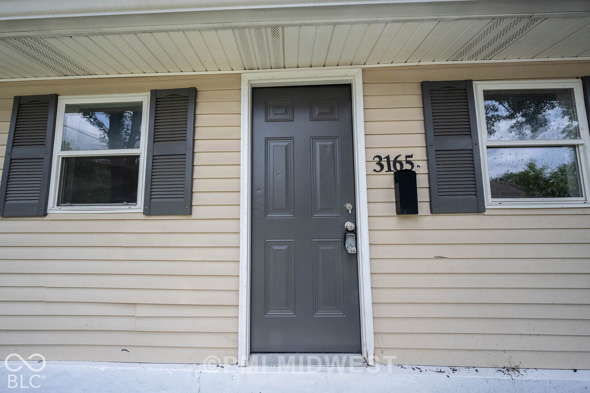 Entry door with dark gray finish, decorative house numbers, and a black mailbox