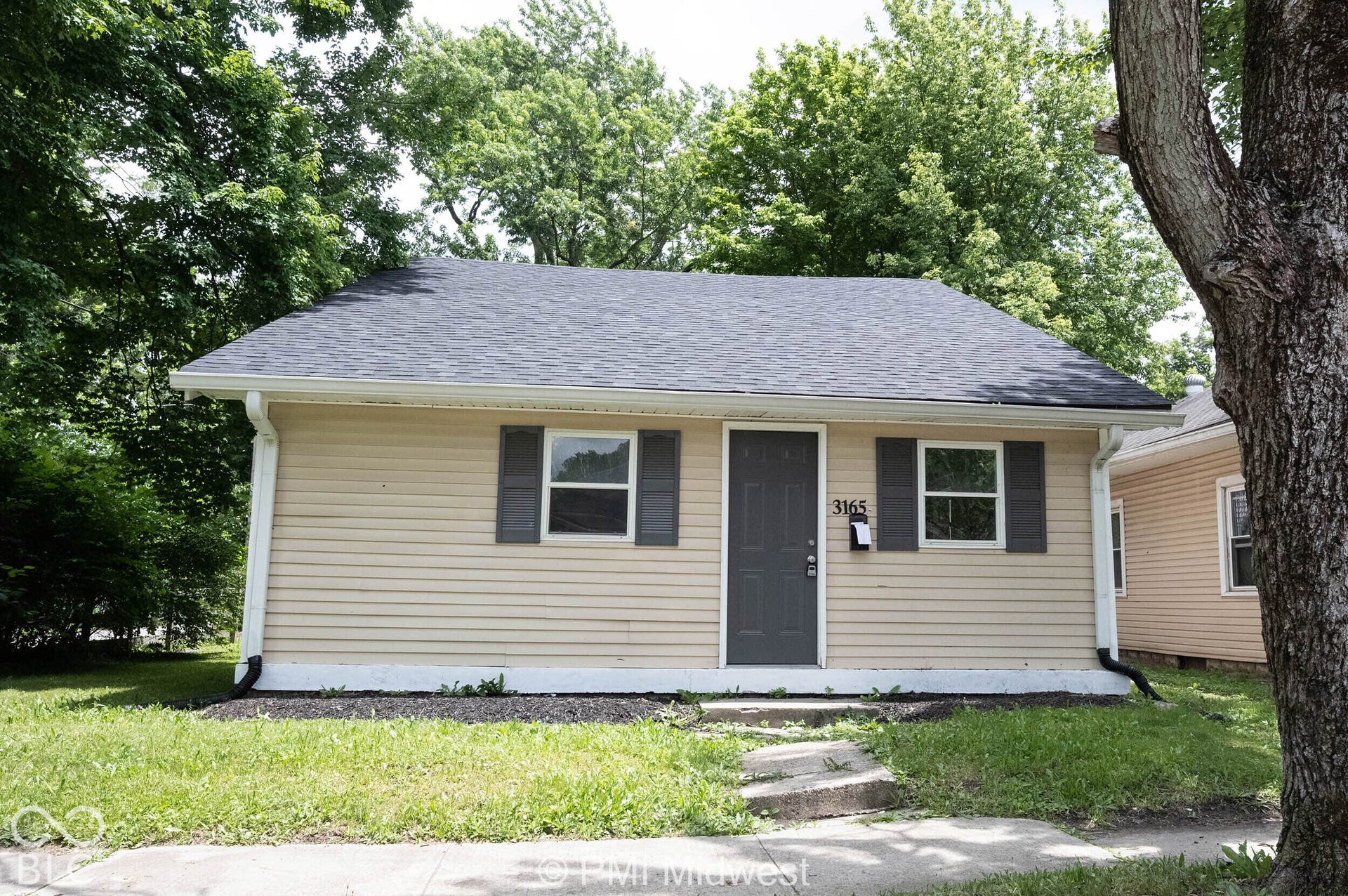 Single-story property featuring light-colored siding, a dark gray roof, and coordinating dark gray shutters
