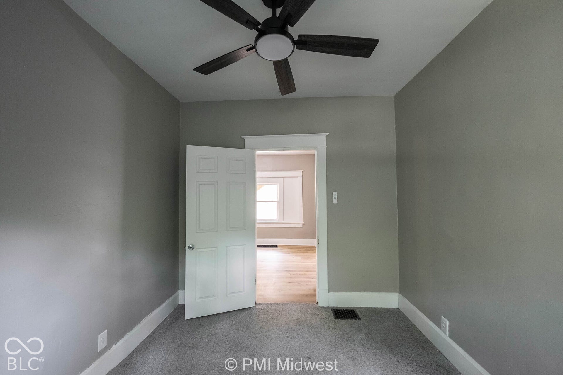 Ceiling fan with integrated lighting, neutral wall paint, white trim, and gray carpet