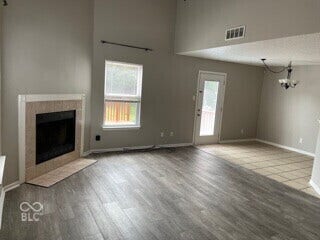 Vaulted ceilings, a tiled fireplace, wood-finish flooring, a full-lite exterior door, and a multi-light chandelier