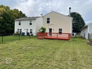 Expansive backyard featuring a wood deck with railings, chain-link fencing, and mature trees beyond the property line