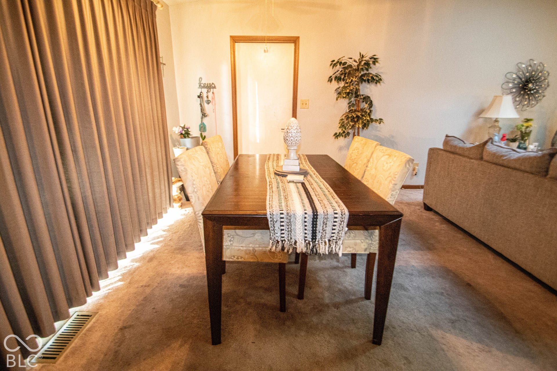 Dark wood-finish dining table and wall-to-wall carpeting