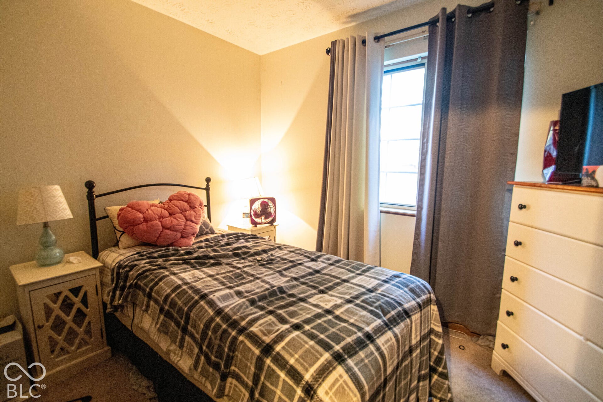 Window with neutral-toned drapes, textured wall finish, and neutral carpeting