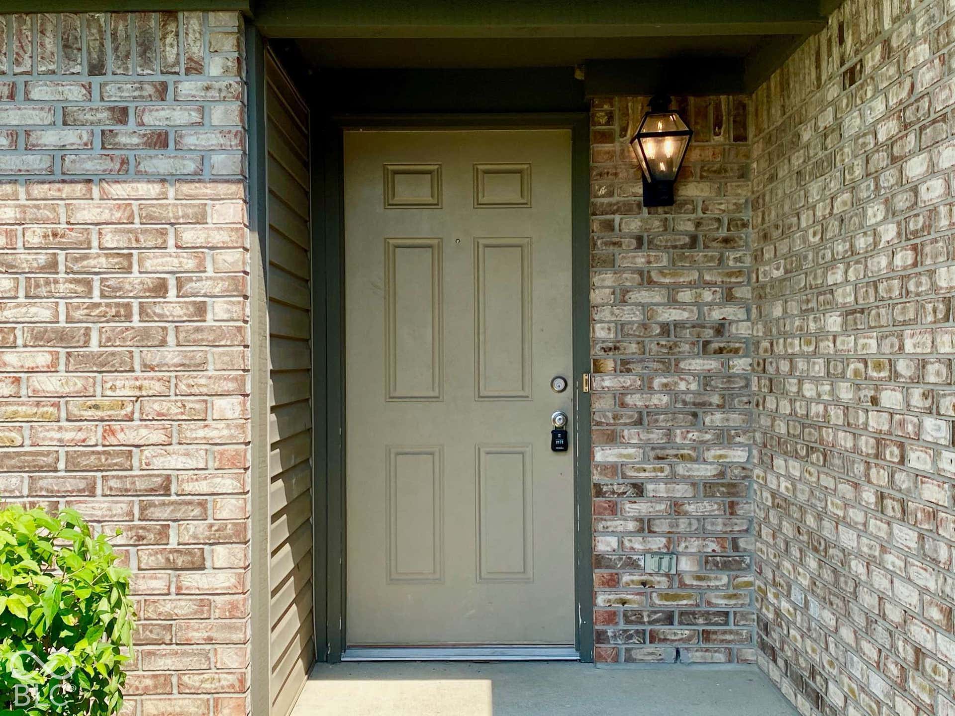 3911 Bonn Drive, Indianapolis, IN 46228 Brick exterior with panel door and wall-mounted lantern light