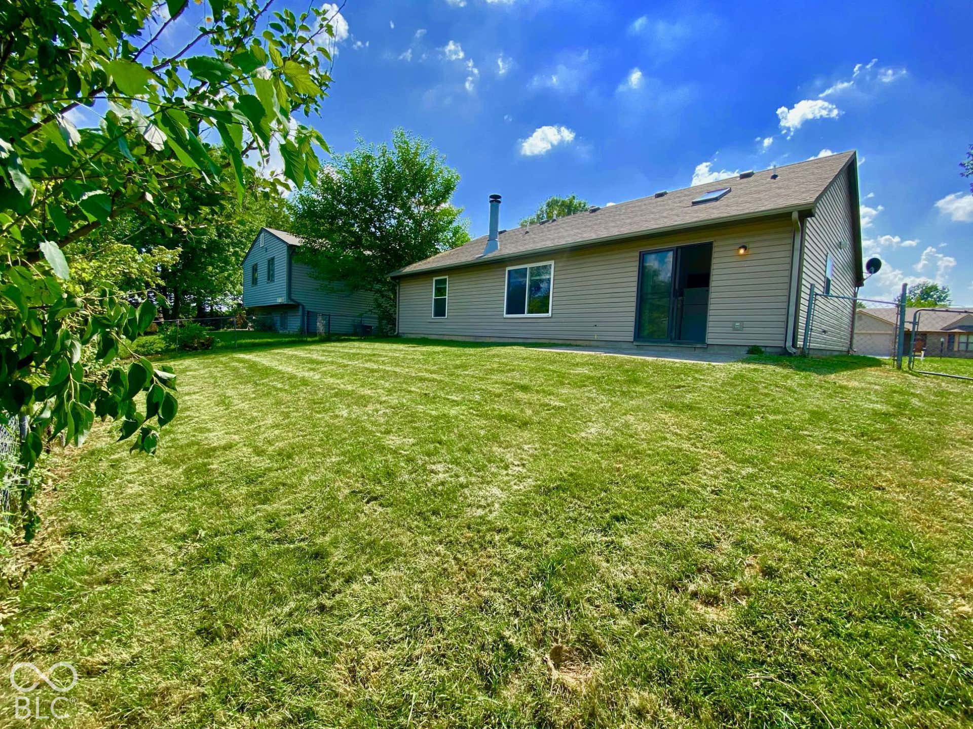 3911 Bonn Drive, Indianapolis, IN 46228 Expansive backyard featuring a manicured lawn, a concrete patio, and mature trees