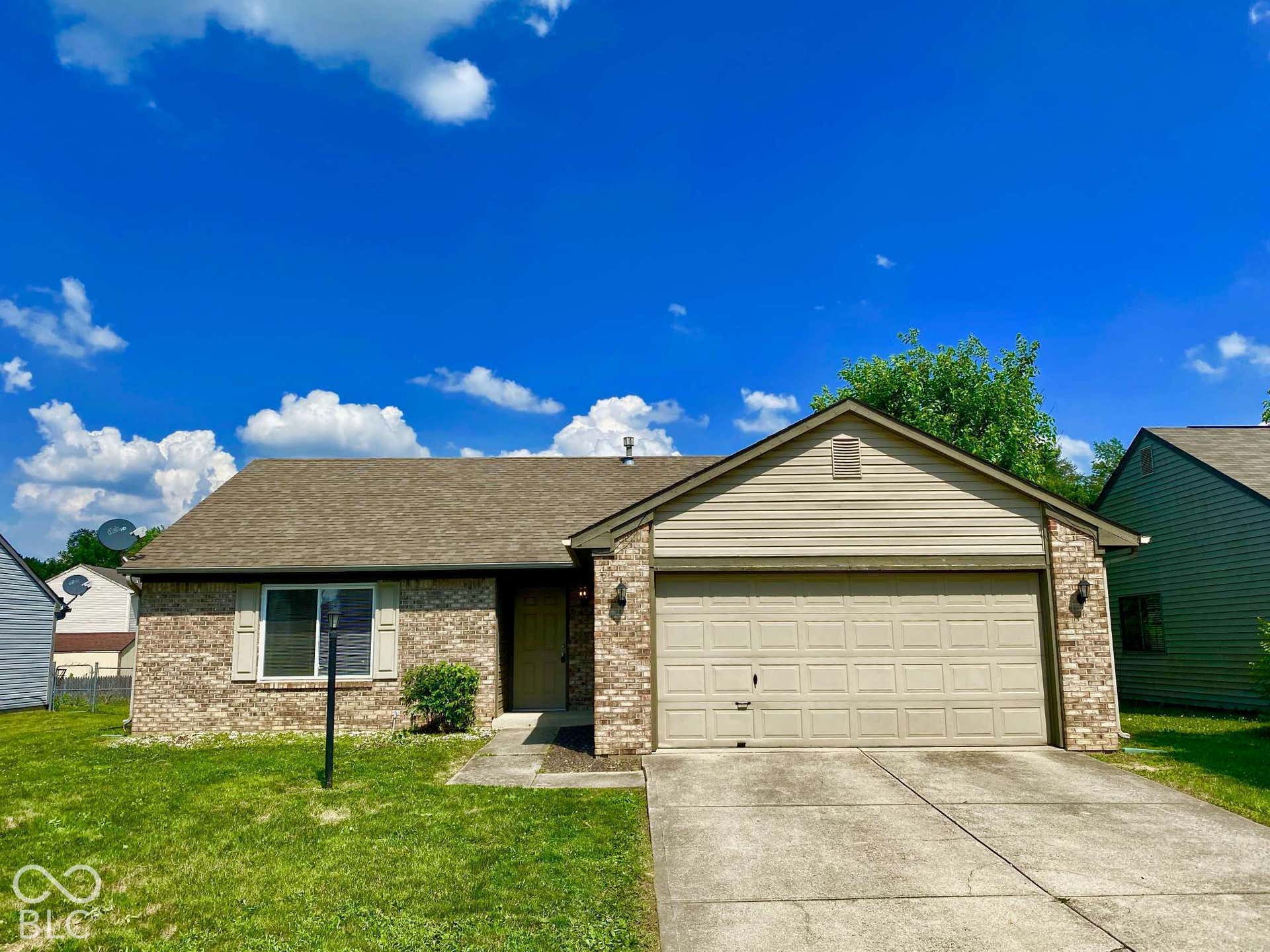 3911 Bonn Drive, Indianapolis, IN 46228 Brick facade with a neutral garage door, concrete driveway, and a shingle roof