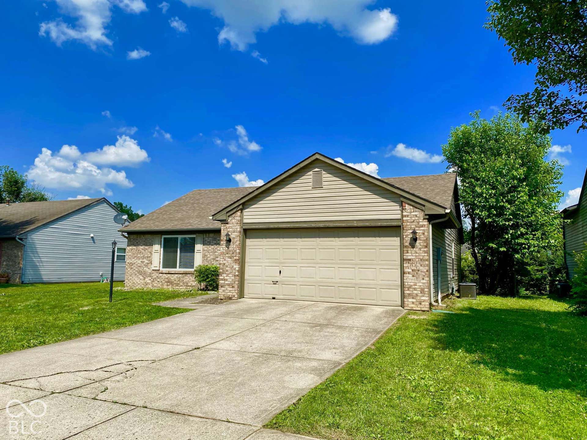 3911 Bonn Drive, Indianapolis, IN 46228 Brick and siding exterior with an attached garage, featuring a concrete driveway and mature landscaping
