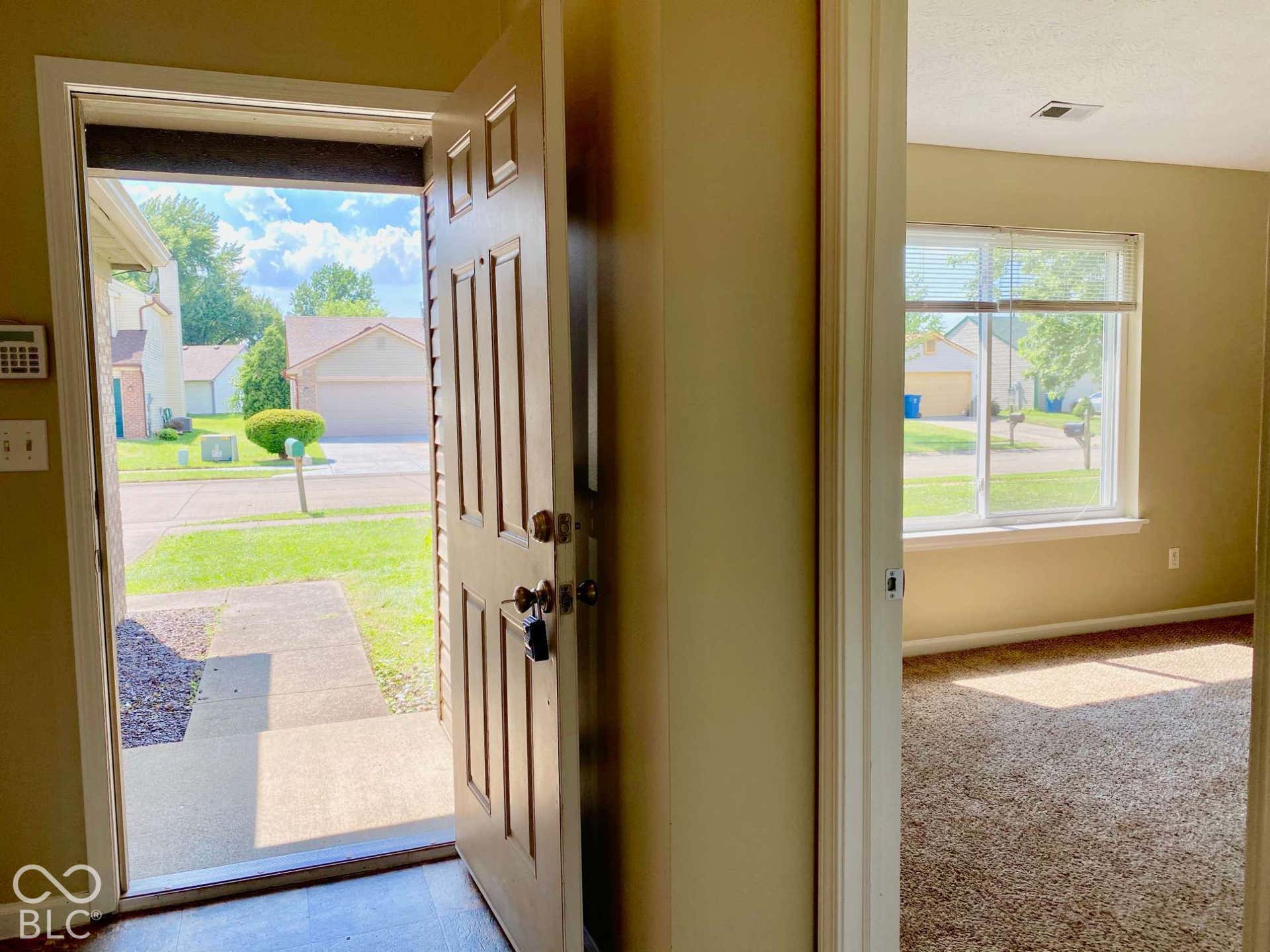 3911 Bonn Drive, Indianapolis, IN 46228 Entryway with a paneled door, leading to an interior with neutral-toned walls and carpeted flooring