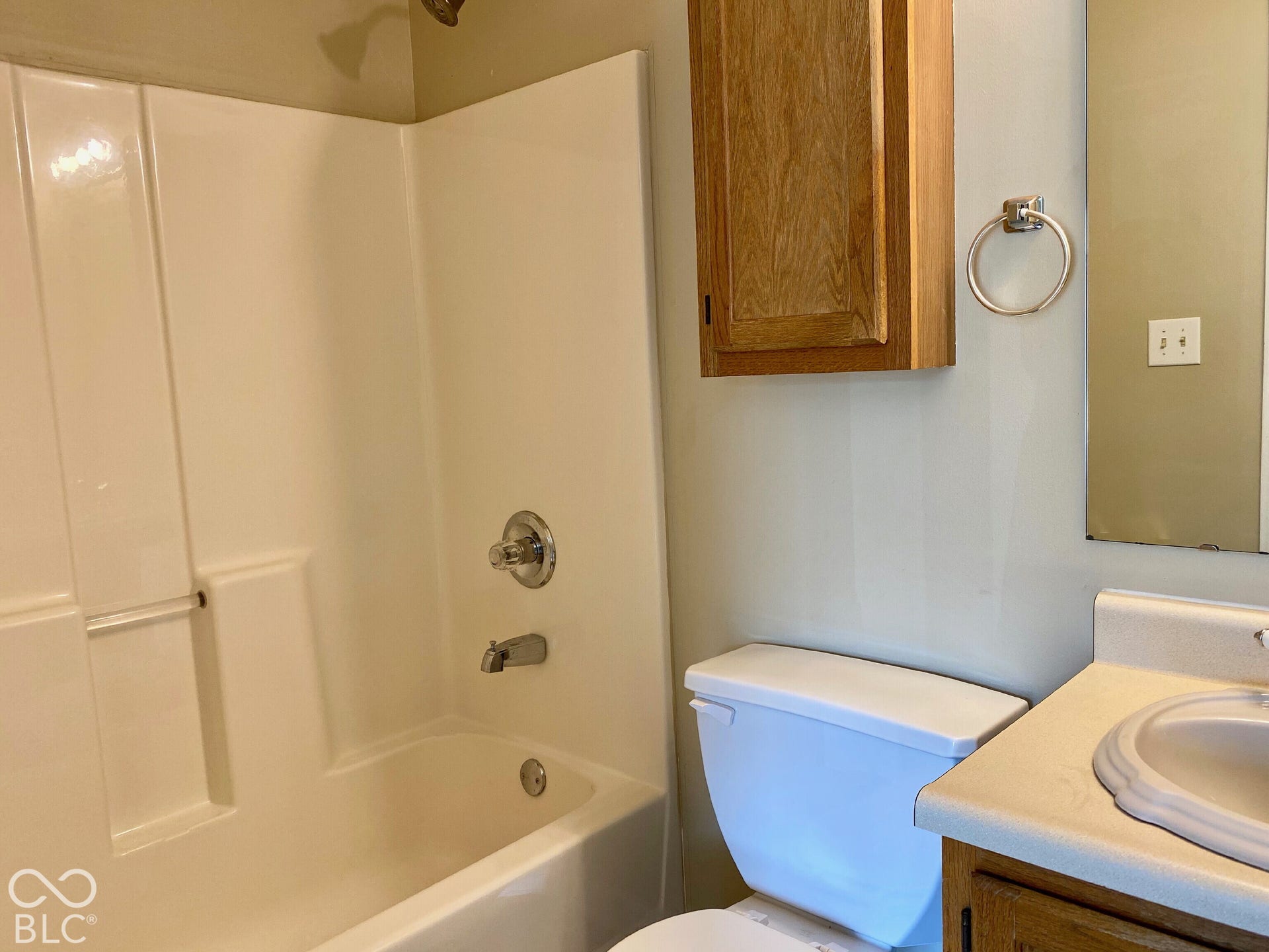 3911 Bonn Drive, Indianapolis, IN 46228 Integrated tub and shower combination with chrome fixtures, wood-finish wall cabinet, toilet, and vanity with an integrated sink