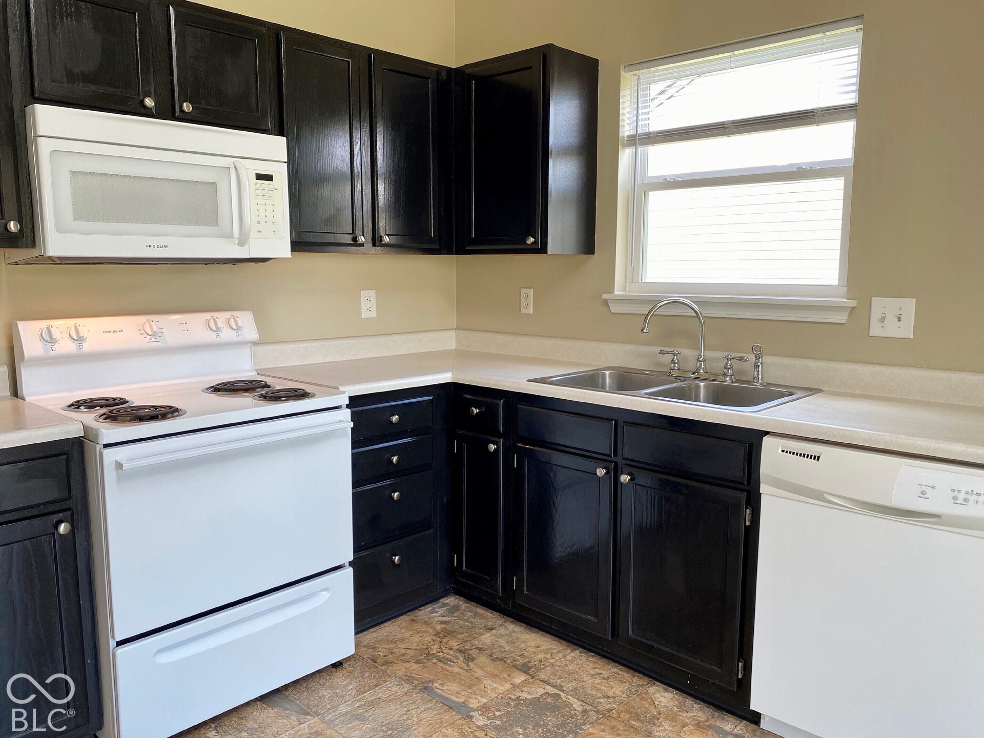3911 Bonn Drive, Indianapolis, IN 46228 Kitchen featuring black cabinetry, white appliances, a dual basin stainless steel sink, and wood-finish flooring