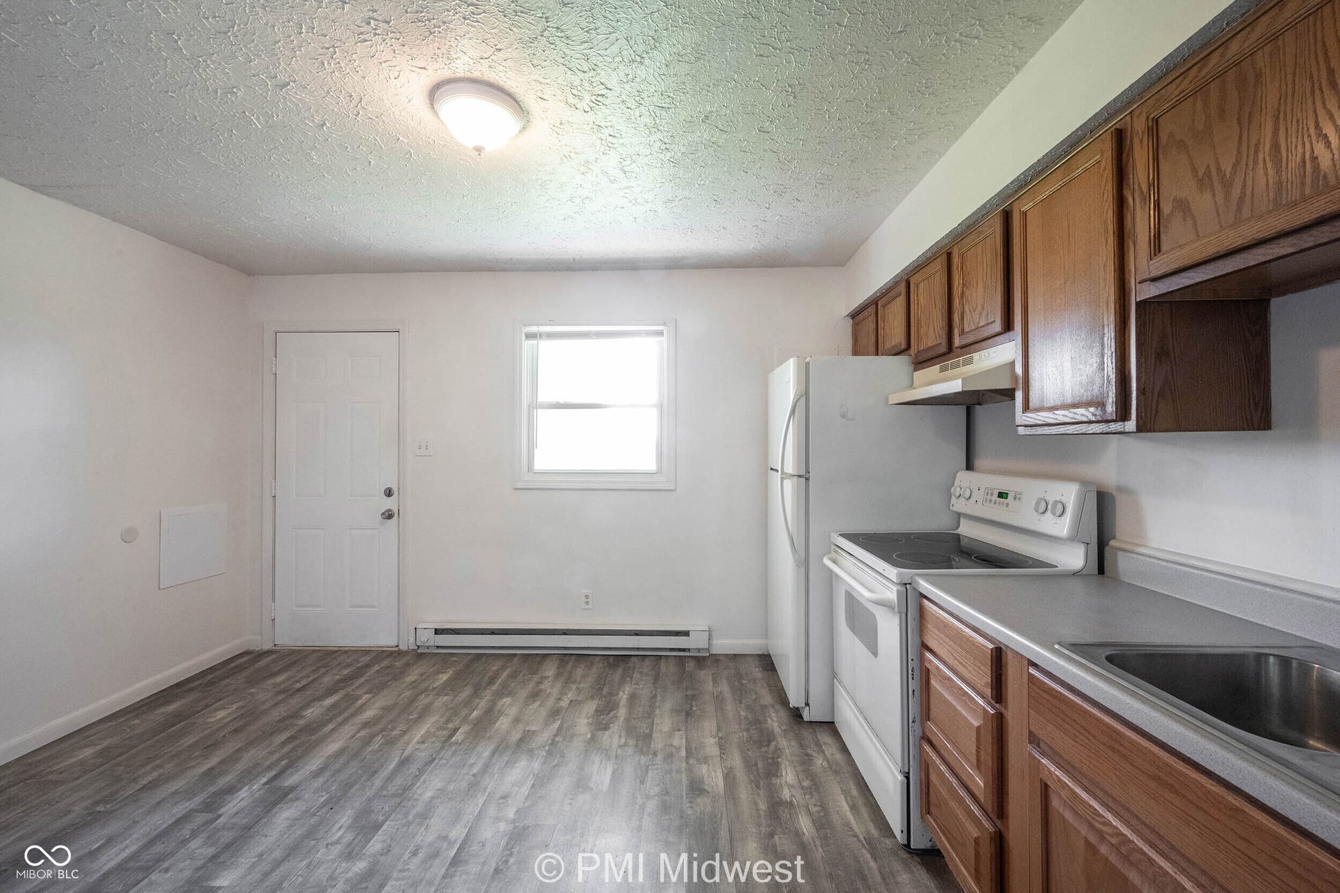 Open kitchen area featuring wood-finish flooring, wood cabinetry, and a double-basin stainless steel sink
