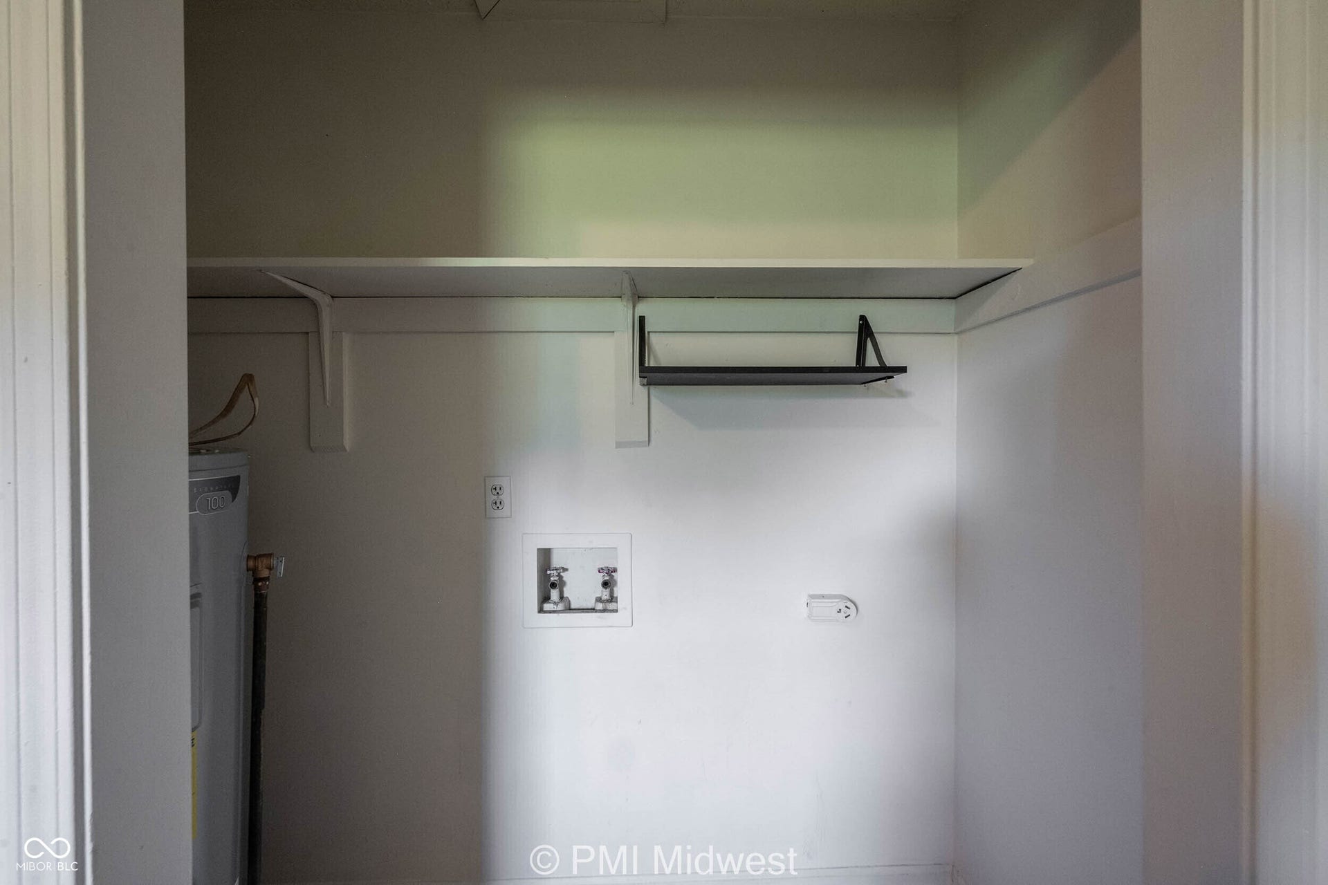 Utility closet featuring a water heater, laundry hookups, and built-in shelving