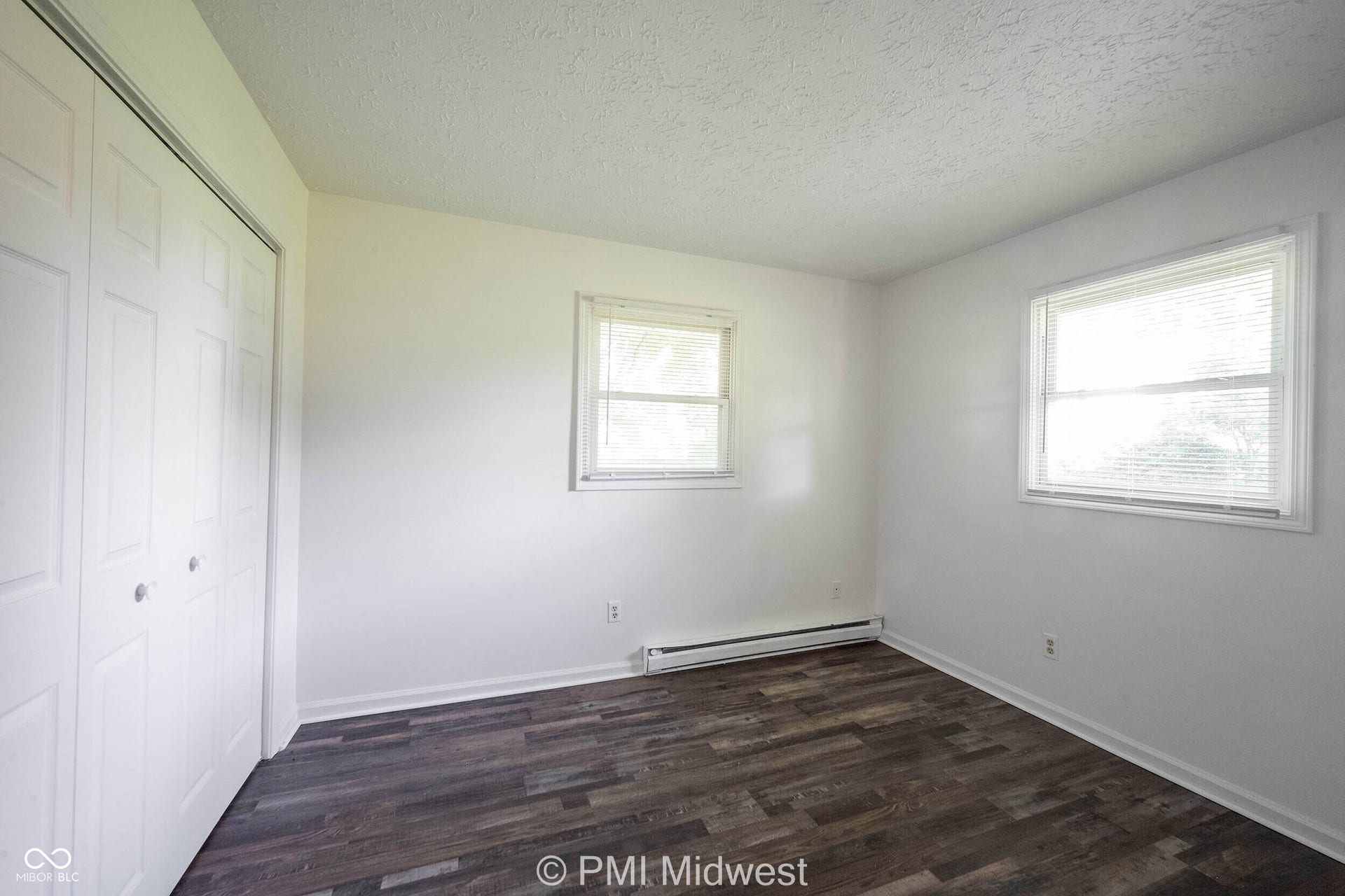 Room featuring wood-finish flooring, white walls, and a textured ceiling