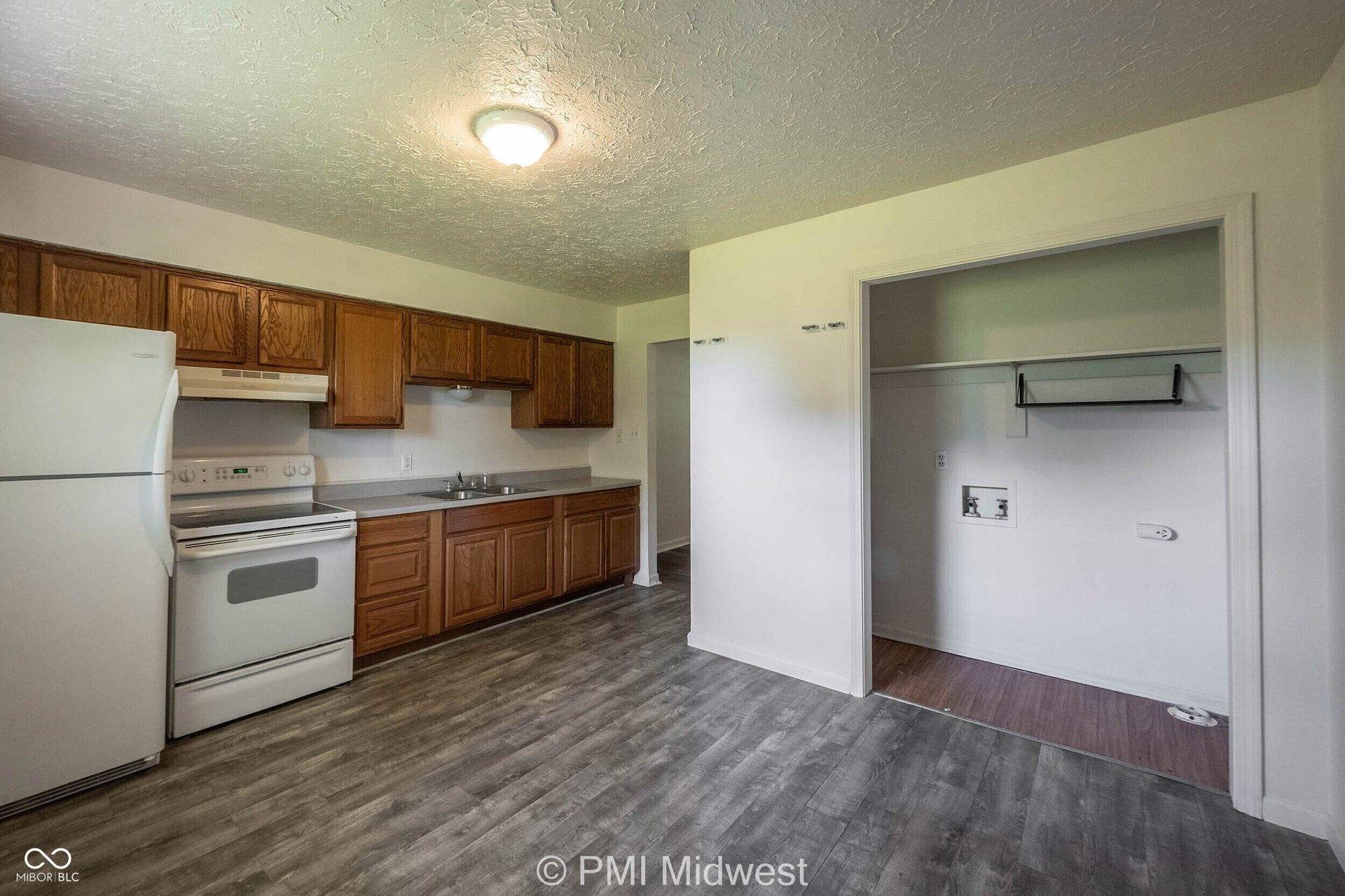 Kitchen area featuring wood-finish flooring, wood cabinetry, a white refrigerator, and a white electric range with a built-in microwave