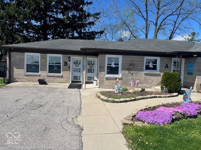 Stone exterior with multiple entryways, paved parking area, and landscaped planting beds