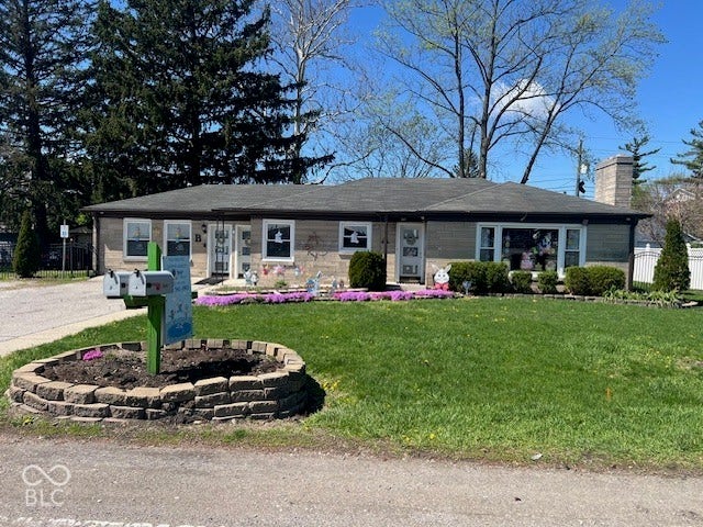 Stone exterior with a dark-shingle roof, well-maintained lawn, and established landscaping