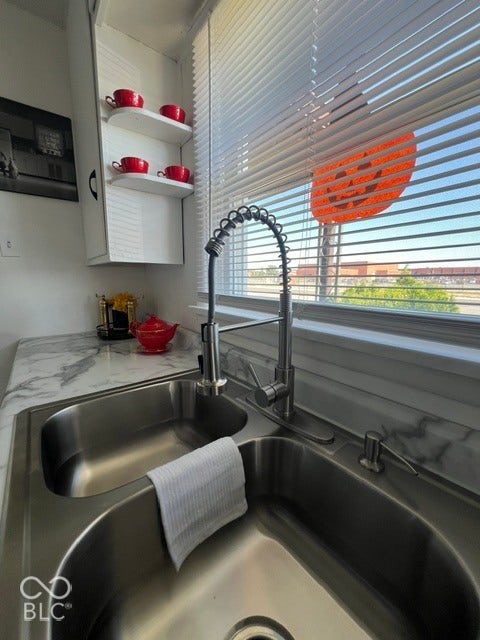 Dual basin stainless steel sink with a high-arc pull-down faucet, complemented by white upper cabinetry and a marble-patterned countertop