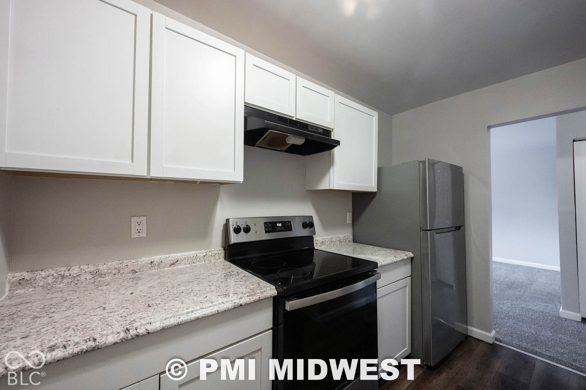 1122 Congress Avenue, Indianapolis, IN 46208 White shaker cabinetry, light-toned countertops, dark wood-finish flooring, and a stainless steel refrigerator
