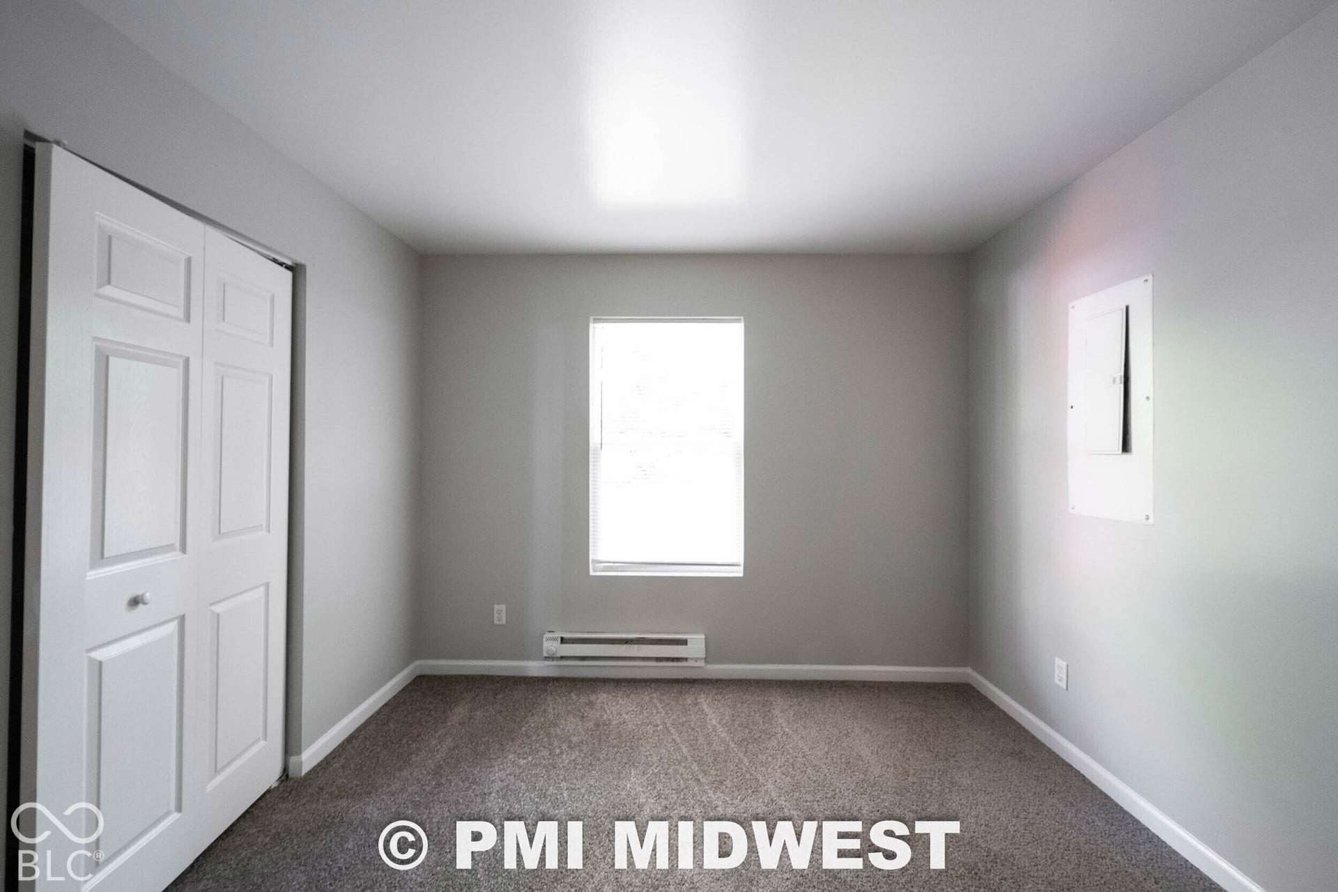 1122 Congress Avenue, Indianapolis, IN 46208 Neutral wall color, carpet flooring, window with blinds, bi-fold closet doors, and a wall-mounted heating unit