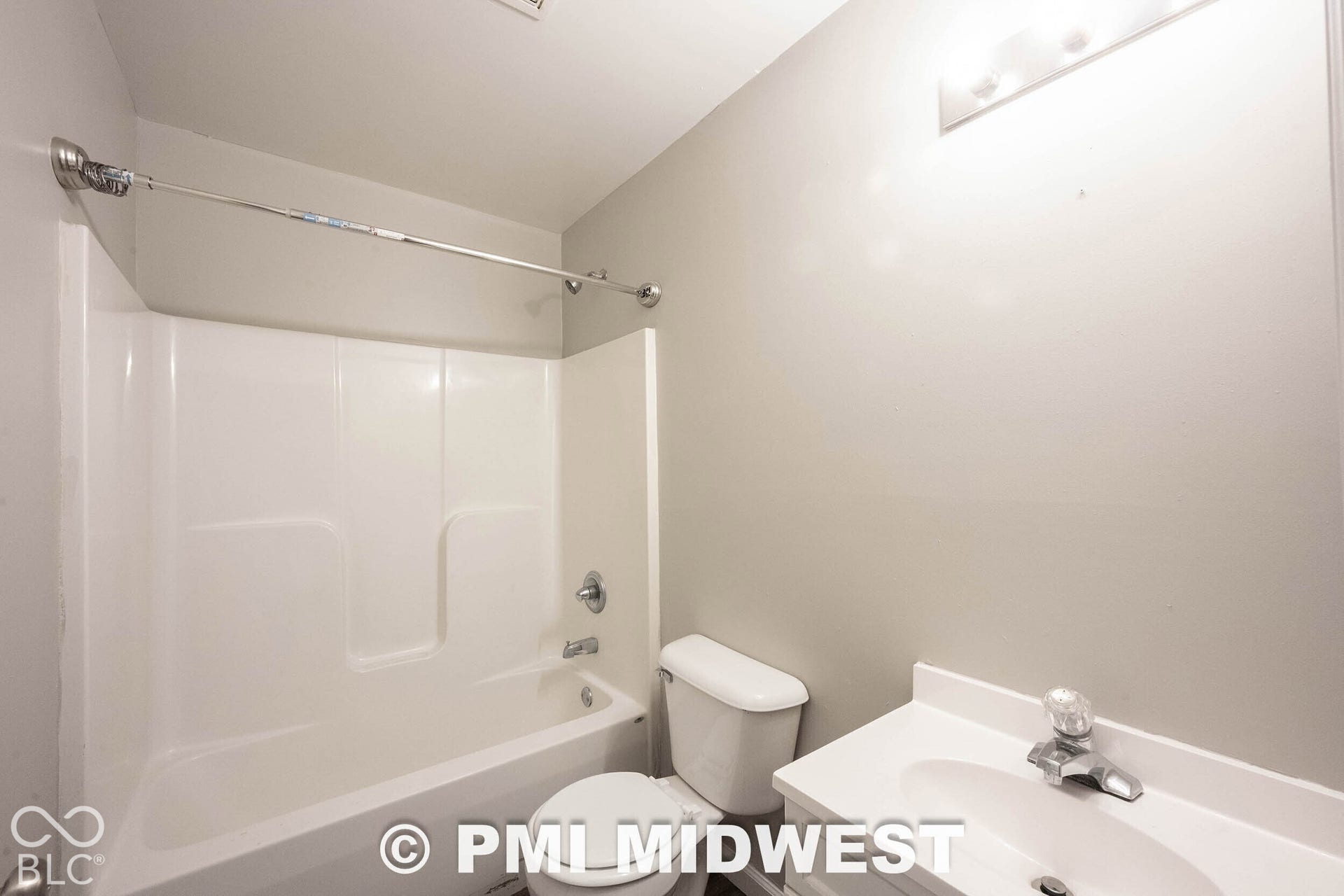 1122 Congress Avenue, Indianapolis, IN 46208 White bathtub and shower combination with chrome fixtures, white toilet, and a vanity with an integrated sink