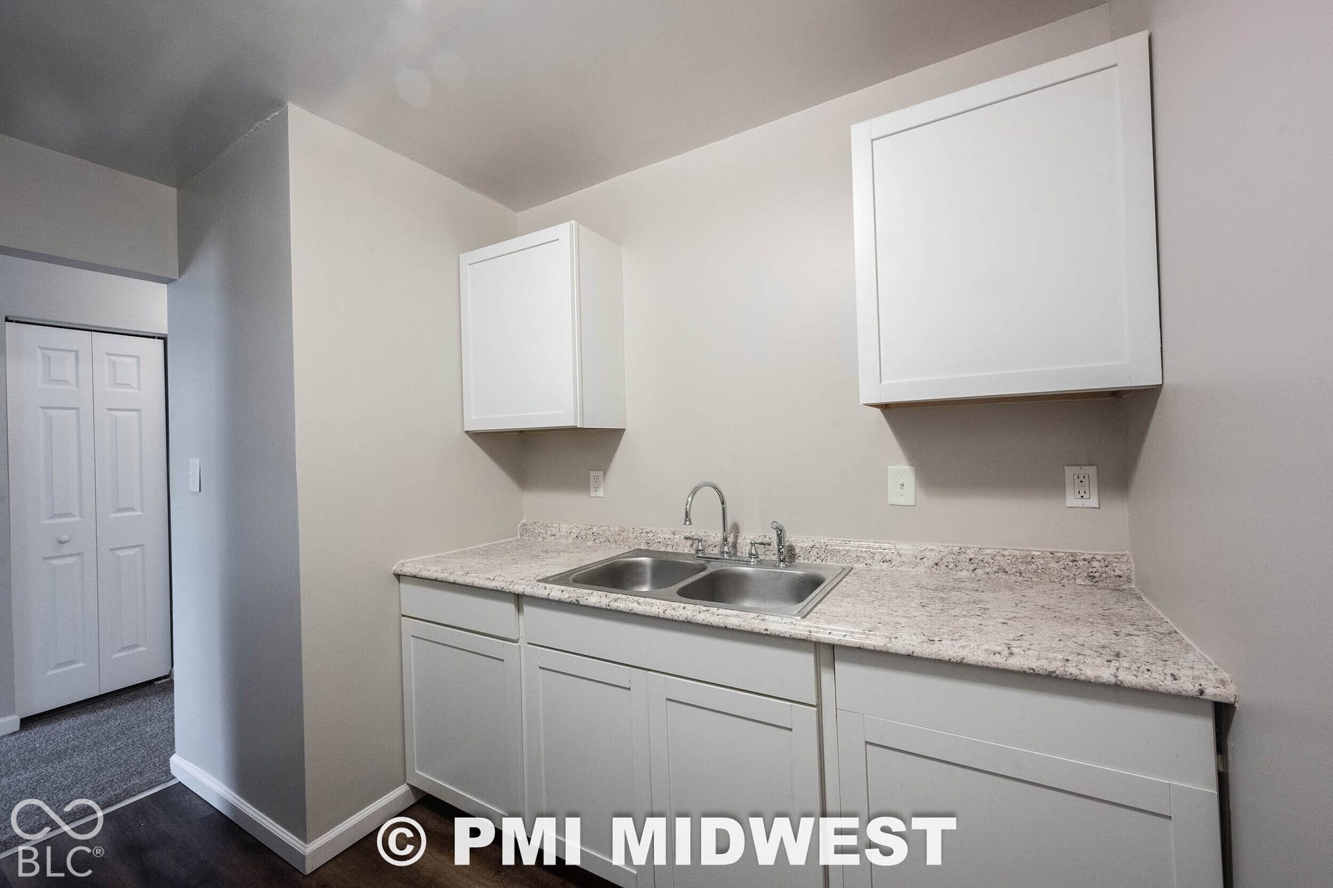 1122 Congress Avenue, Indianapolis, IN 46208 White shaker-style cabinetry, double basin stainless steel sink, speckled laminate countertops, and wood-finish flooring