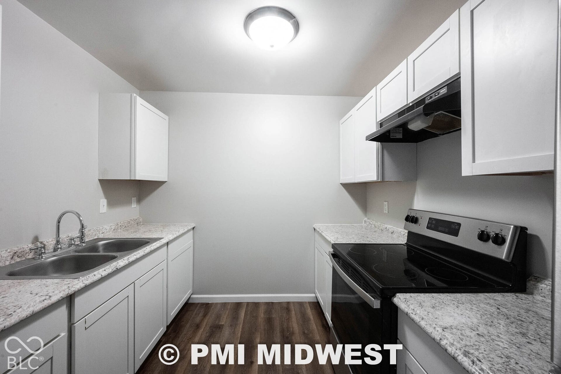 1122 Congress Avenue, Indianapolis, IN 46208 White cabinetry with black hardware, wood-finish flooring, stainless steel double basin sink, stainless steel electric range, and light-colored speckled countertops