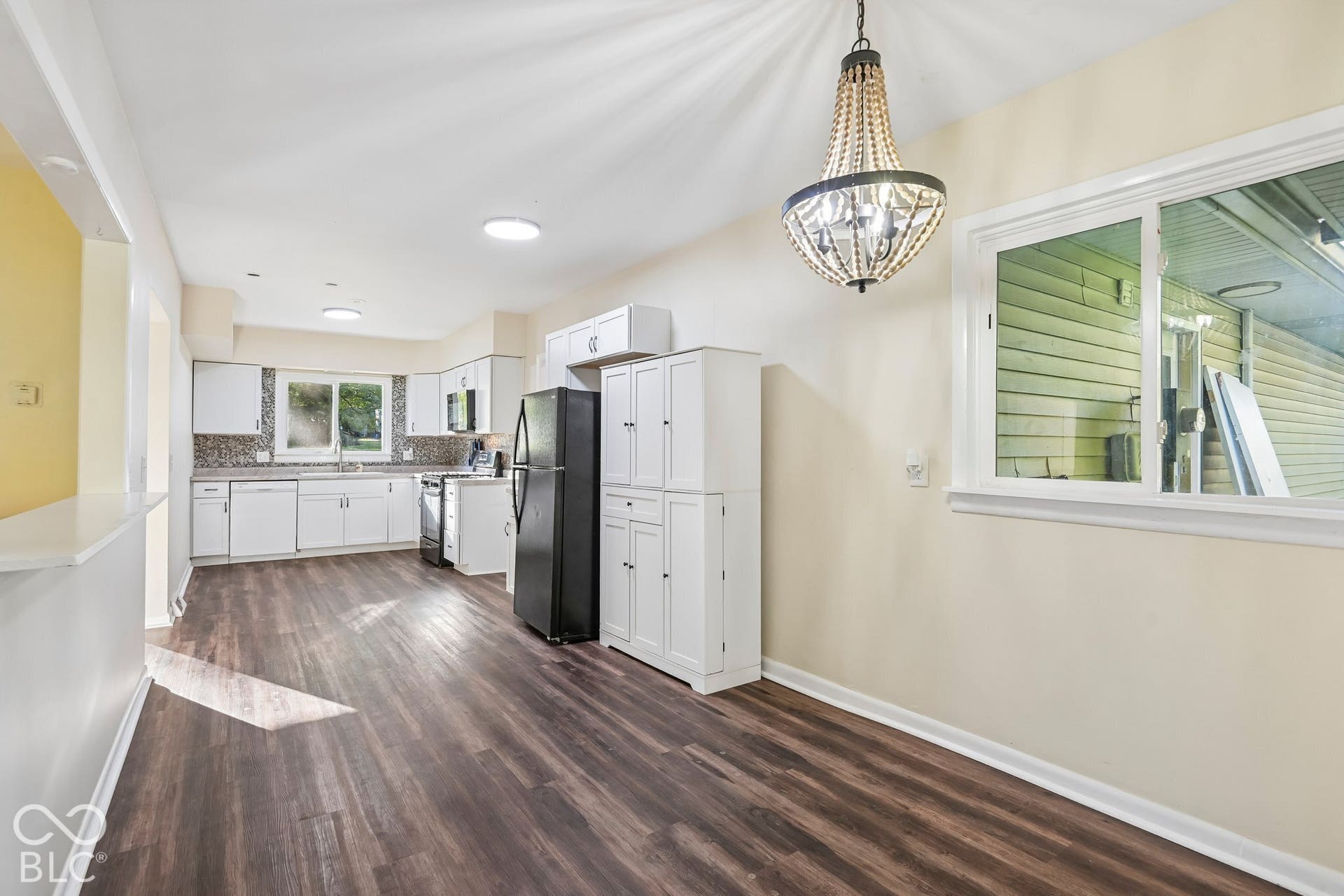 Spacious kitchen with white cabinetry, dark wood-finish flooring, and a decorative beaded chandelier