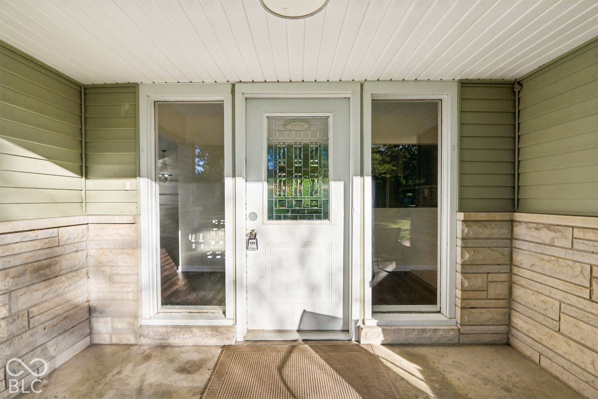 Covered entryway featuring French doors with multi-pane glass panels, white painted trim, and a welcoming entrance mat