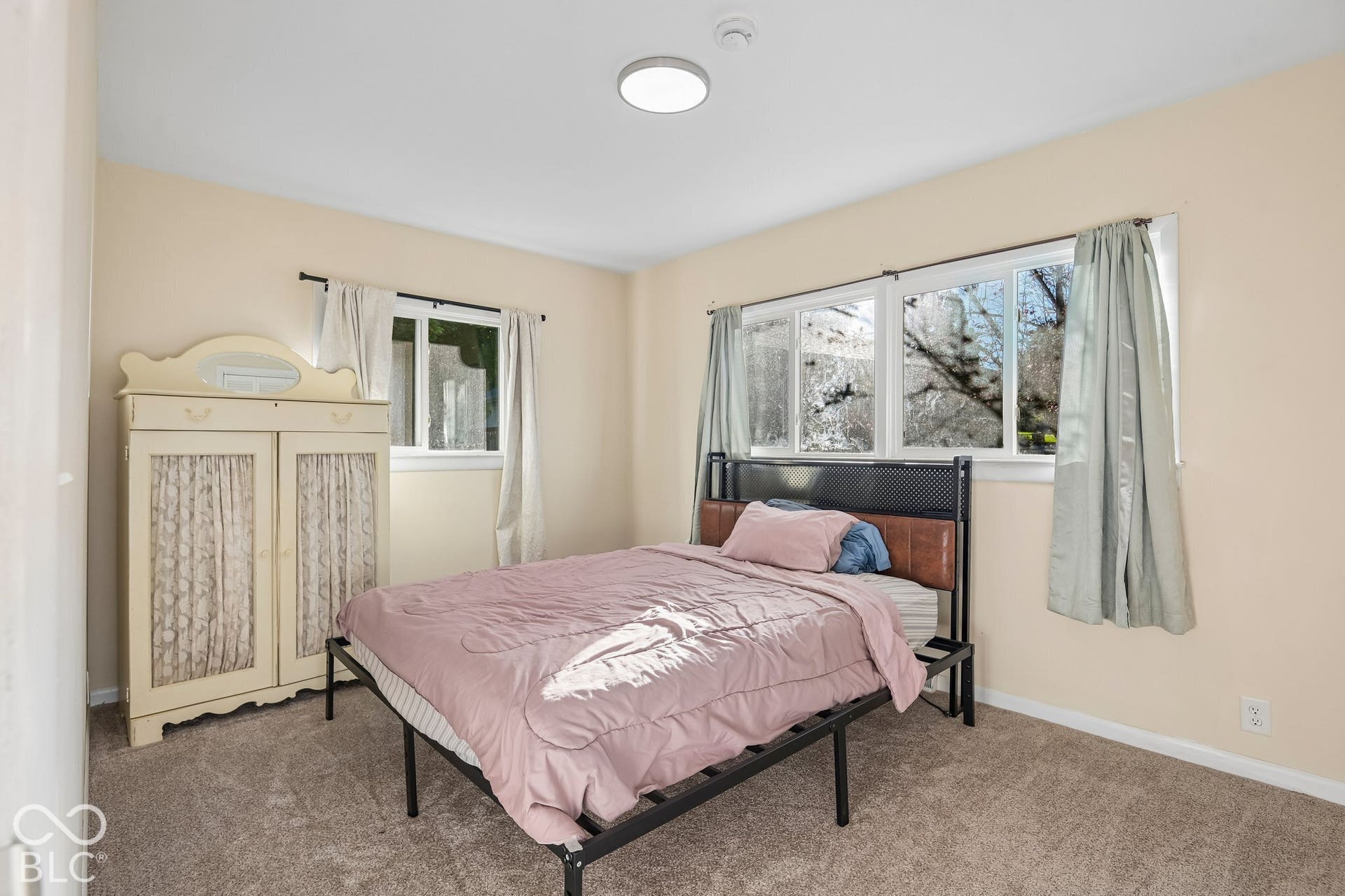 Carpeted room with multiple windows, a ceiling-mounted light fixture, and neutral-toned walls