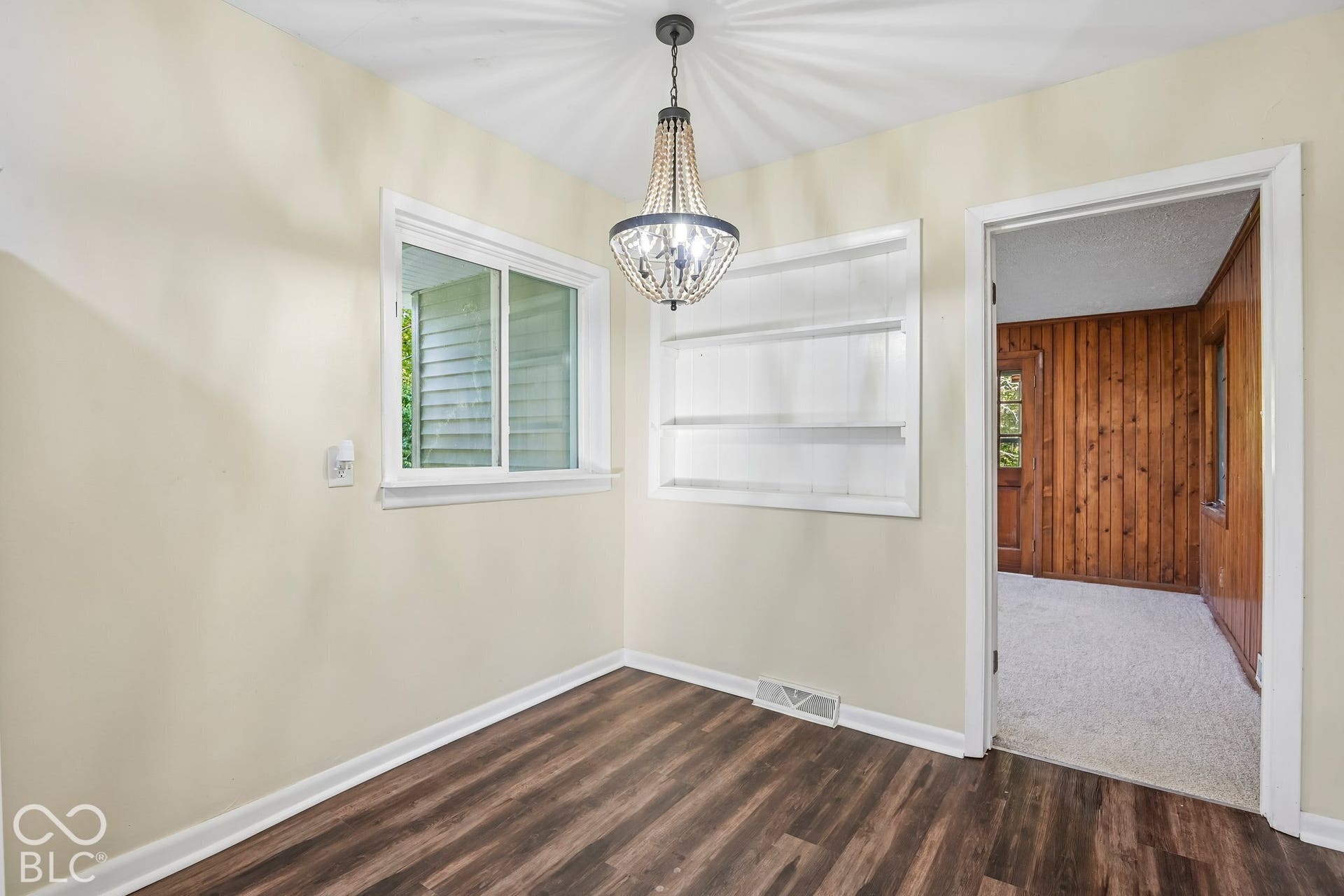 Wood-finish flooring with light-toned walls, white trim, and a white window frame