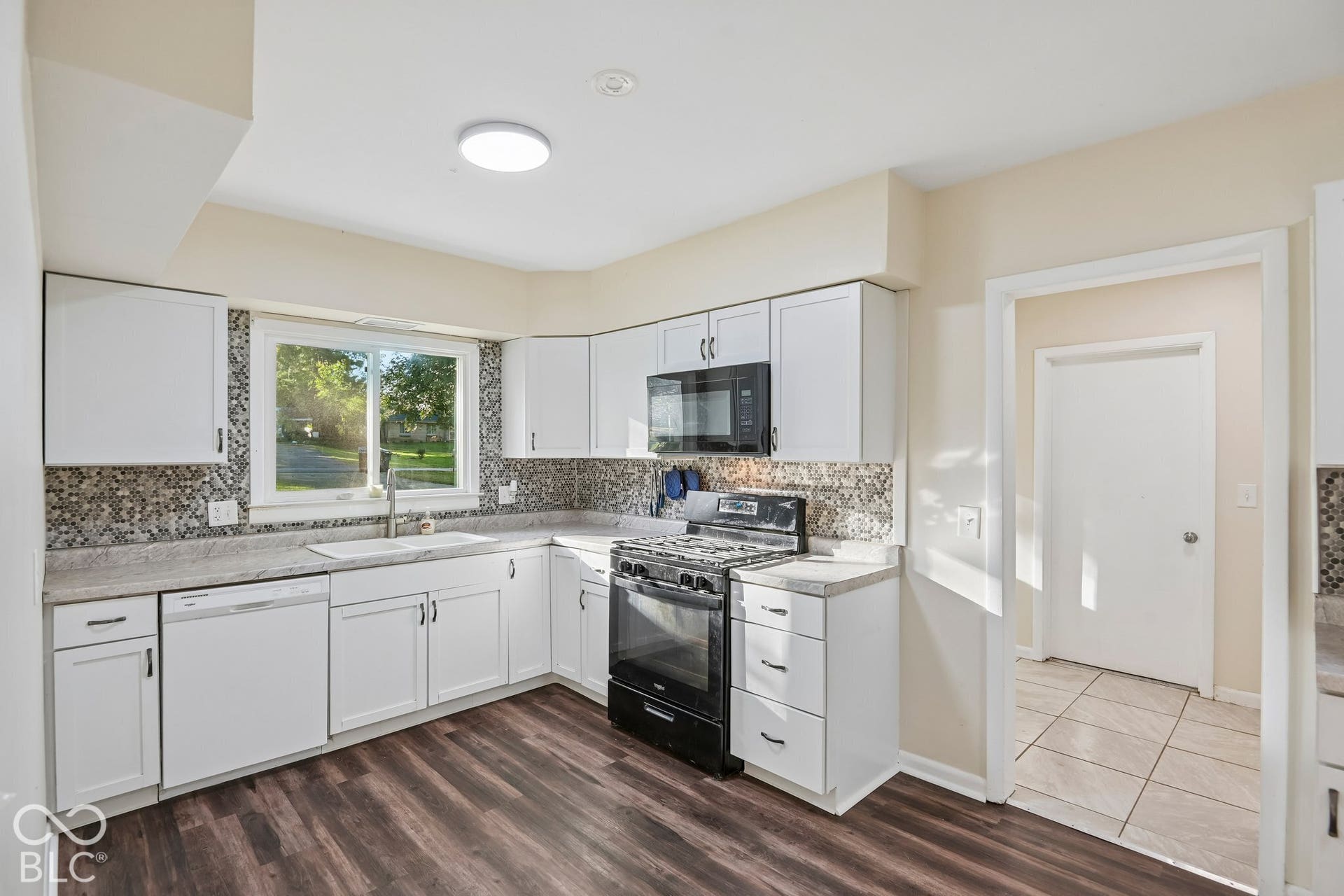 Kitchen featuring white cabinetry, dark wood-finish flooring, a mosaic tile backsplash, and a white basin sink with a single-handle faucet
