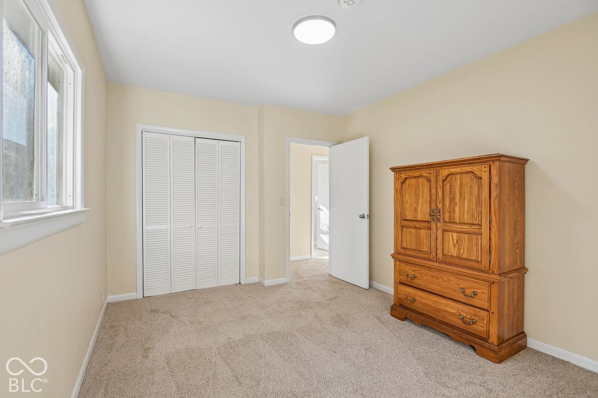 Spacious bedroom with neutral wall finishes, recessed ceiling lighting, large closet with louvered doors, and carpet flooring