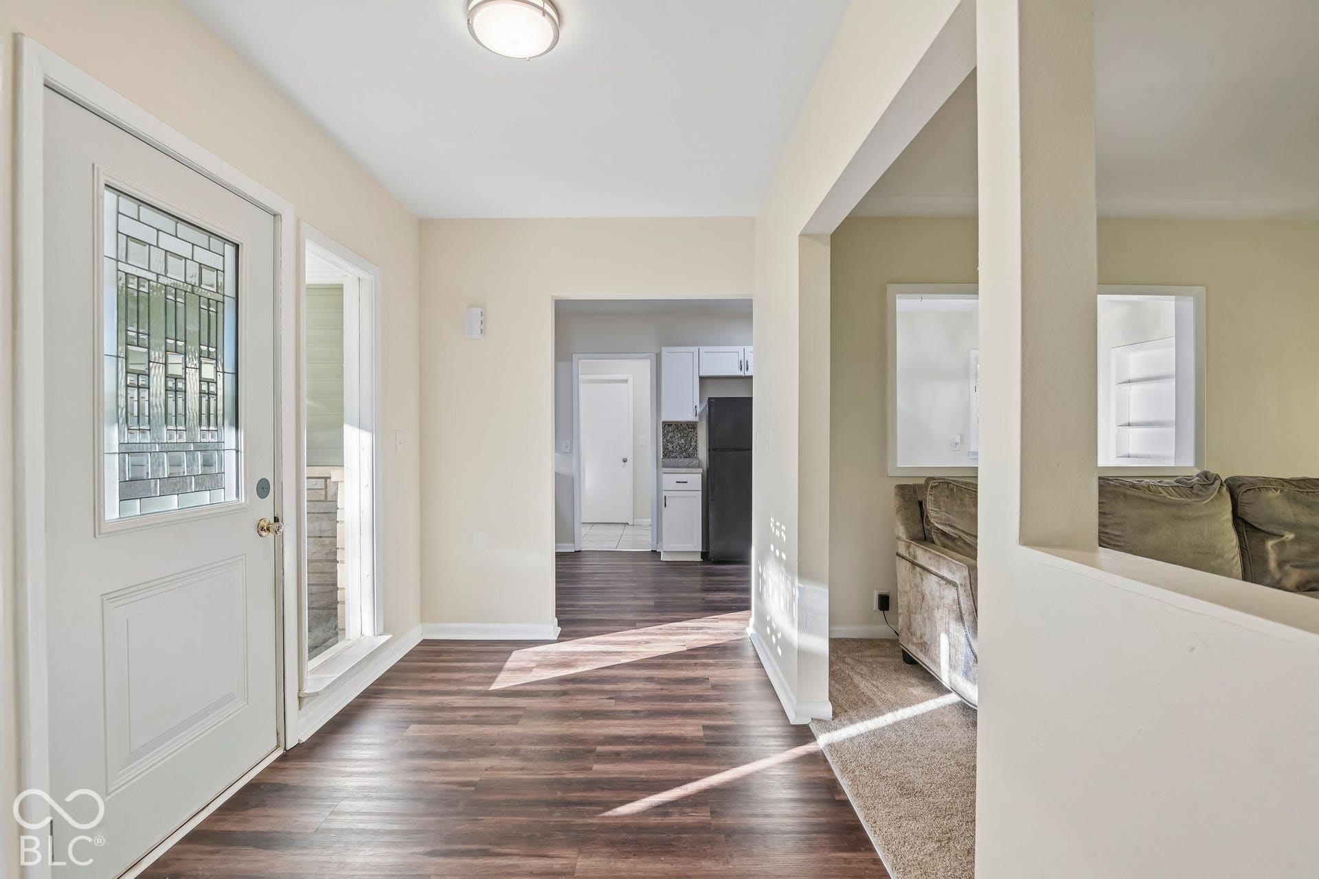 Entryway featuring a white door with decorative glass, sidelight, wood-finish flooring, and a flush-mount ceiling light