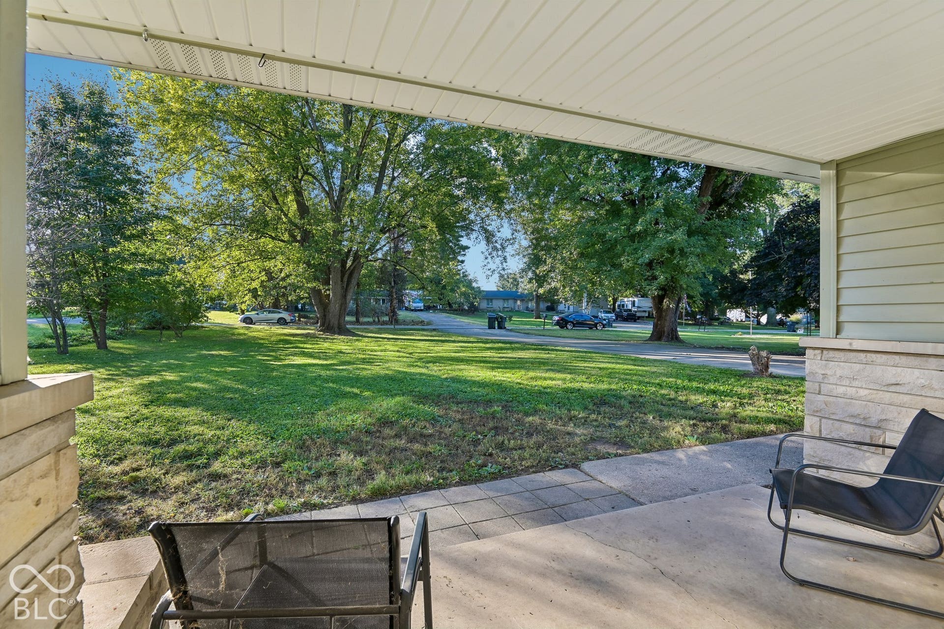 Covered porch featuring concrete flooring and stone-clad support pillars