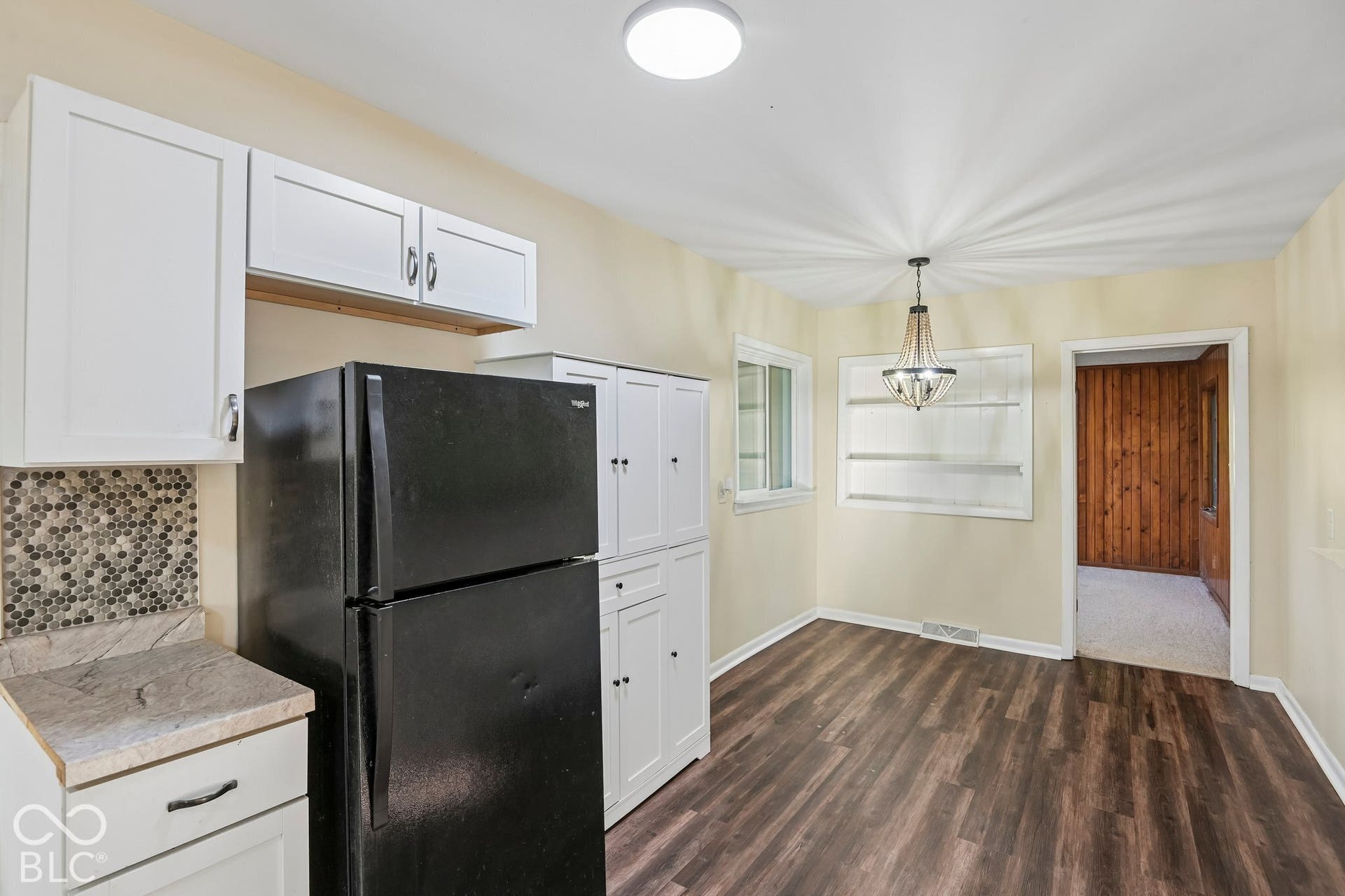 Kitchen featuring white shaker-style cabinetry, mosaic tile backsplash, and wood-finish flooring