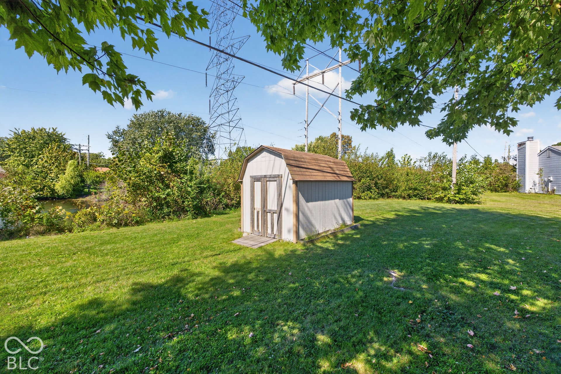 Expansive grassy yard featuring a storage shed with a shingle roof
