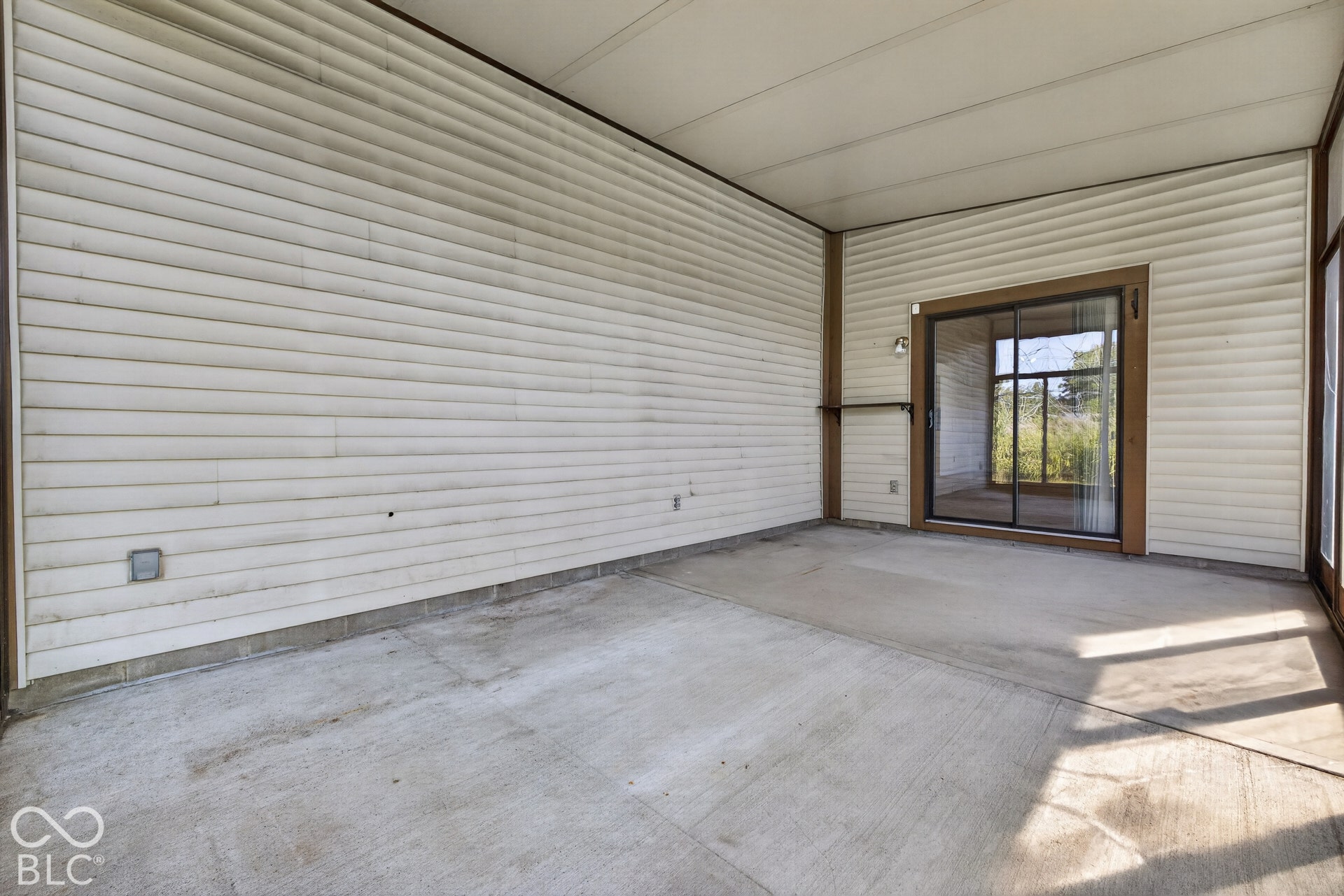 Sliding glass door, concrete flooring, ribbed paneling, built-in shelving, exterior lighting fixture