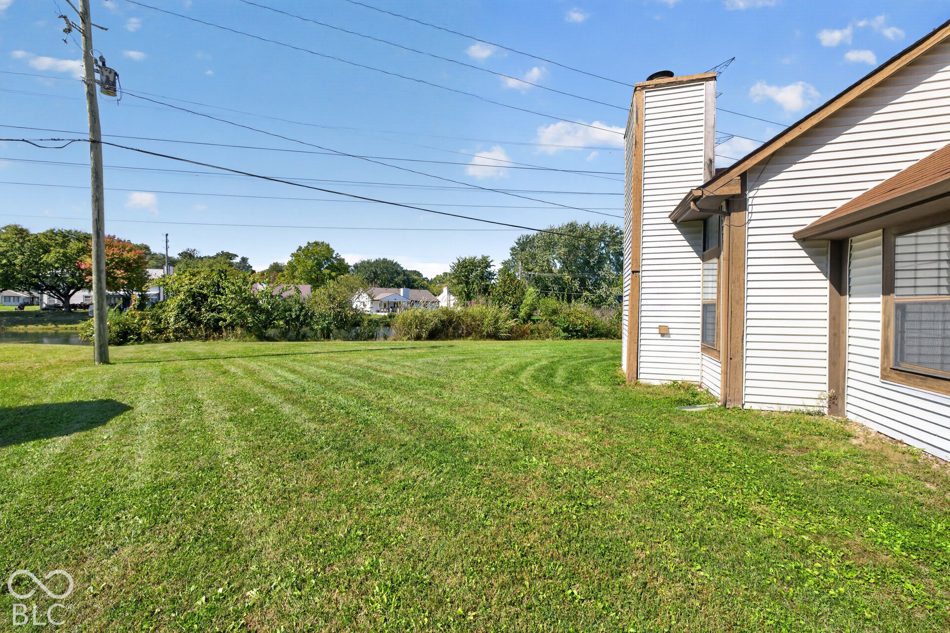Siding exterior with a prominent chimney structure and multiple windows with horizontal blinds