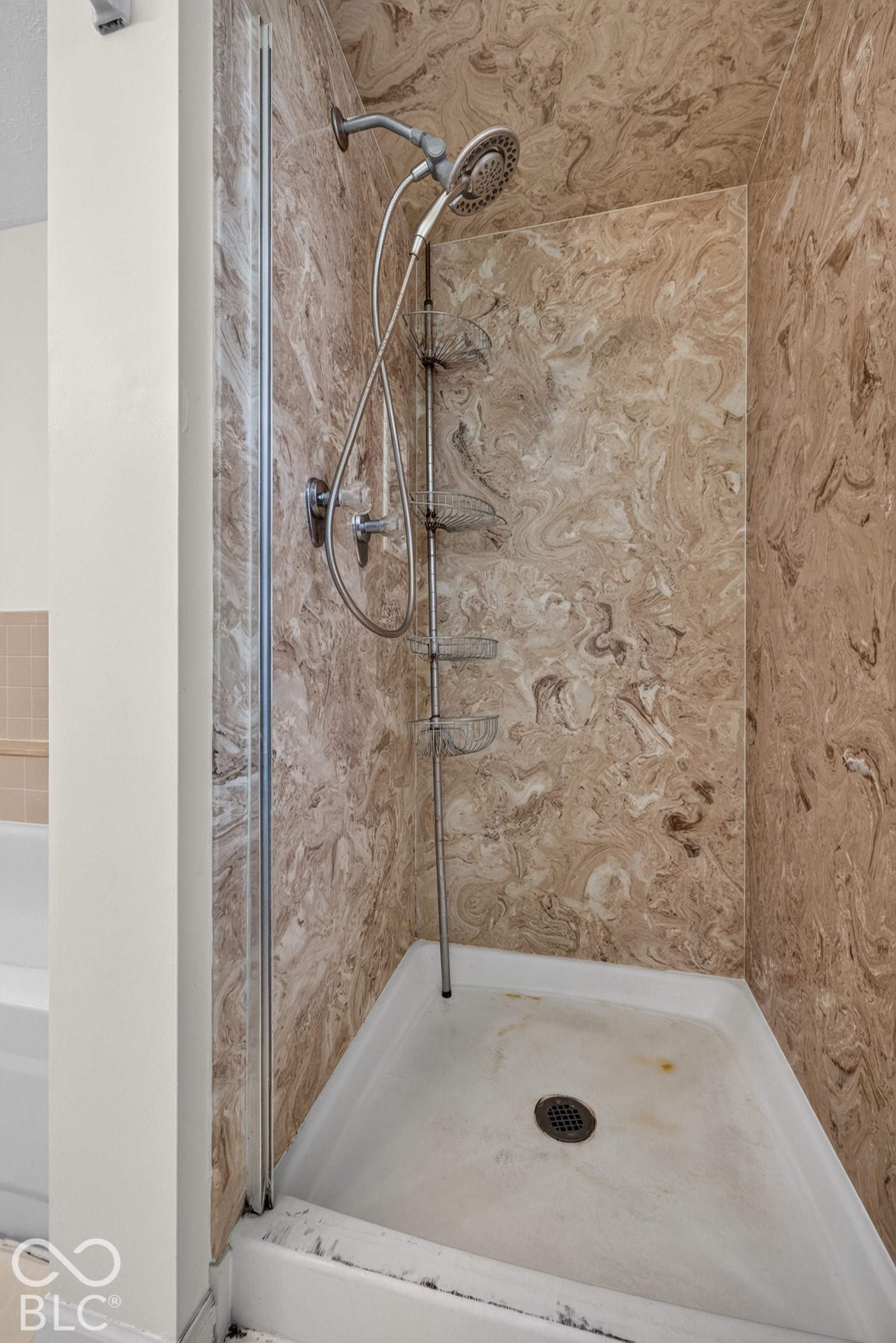 Walk-in shower with textured wall panels and a handheld showerhead