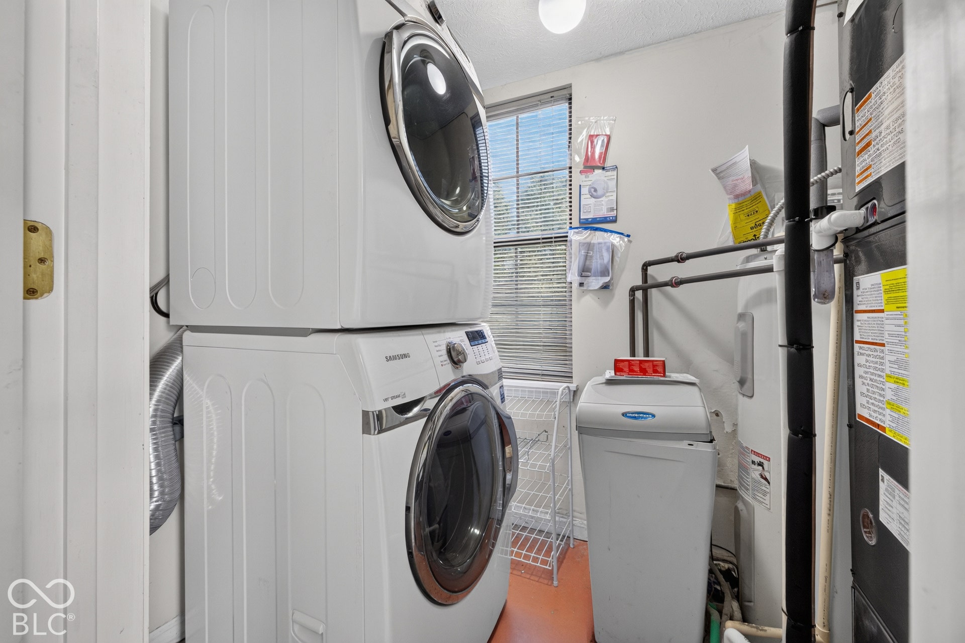 Dedicated utility space with stacked washer and dryer, water heater, and water softener