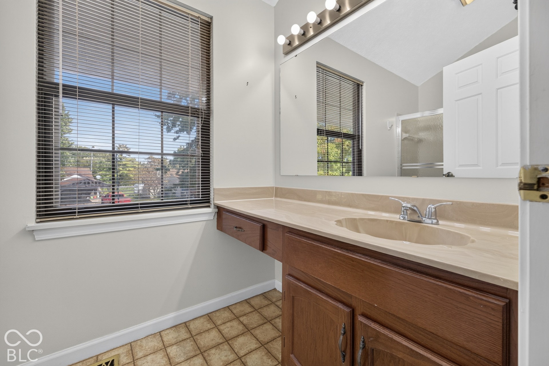 Single vanity with integrated sink, wood-finish cabinetry, and a full-width mirror