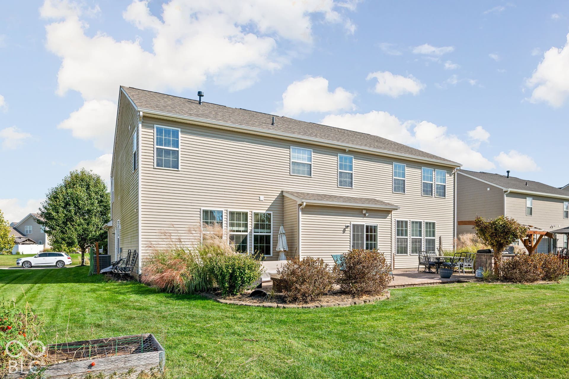 Two-story exterior with light-toned siding, a rear patio, and a spacious lawn