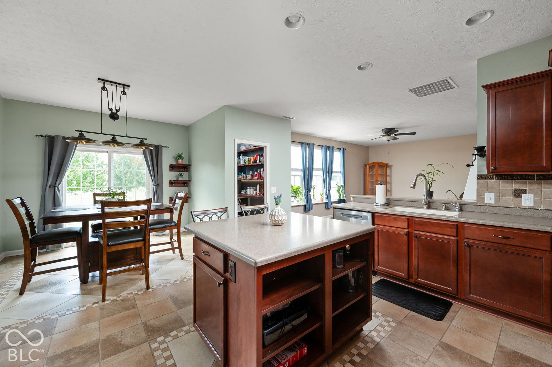 Kitchen featuring a center island, wood-finish cabinetry, tile flooring with decorative accents, recessed lighting, and a pantry with shelving