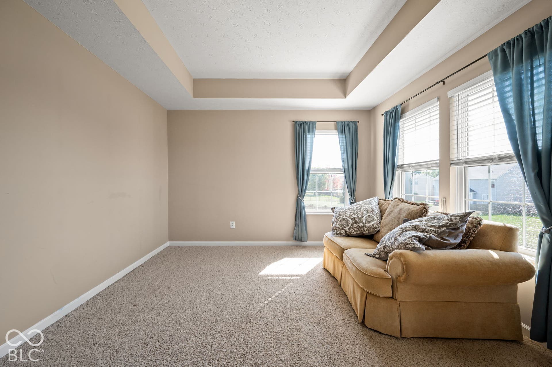 Sitting Room in Primary Bedroom. Tray ceiling, neutral wall tones, two large windows, two smaller windows, and carpeted flooring