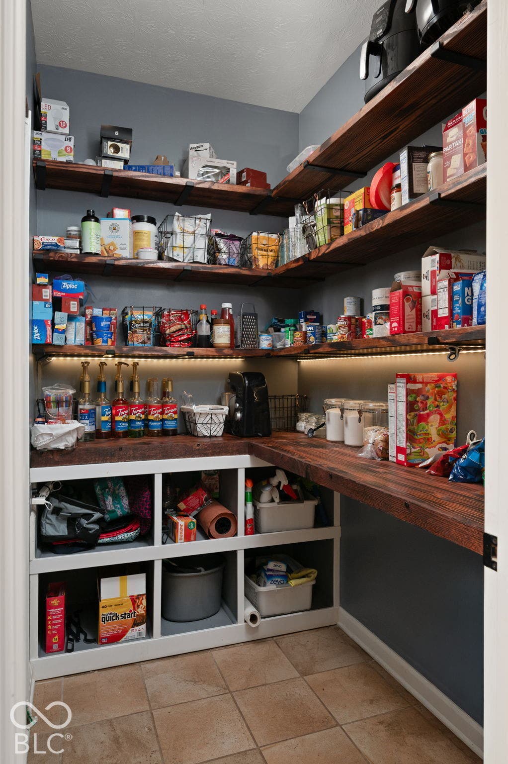 Built-in wood-finish shelving and countertops, under-shelf lighting, and tile flooring