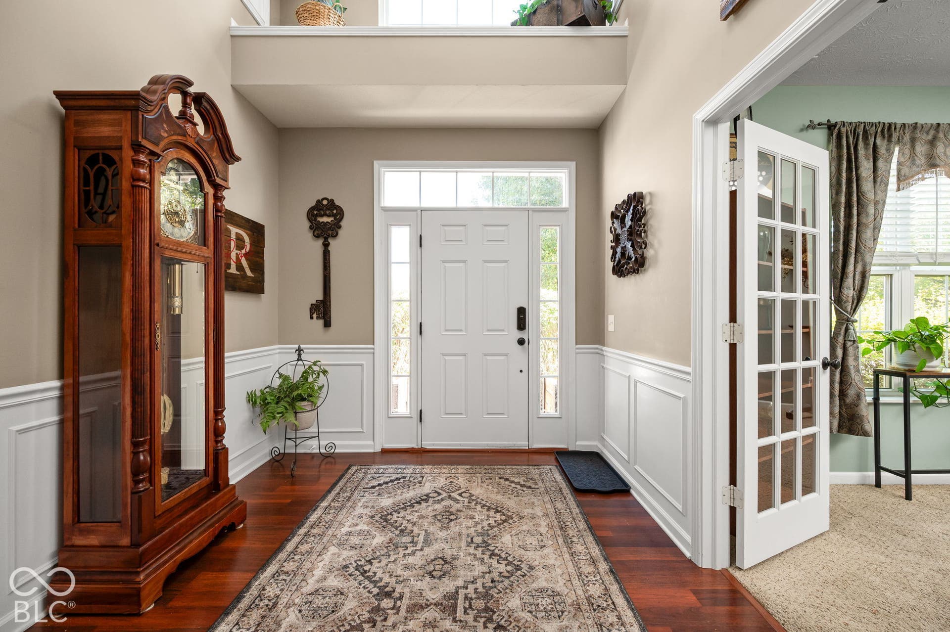 Bright entryway featuring wood-finish flooring, wainscoting, and a transom window