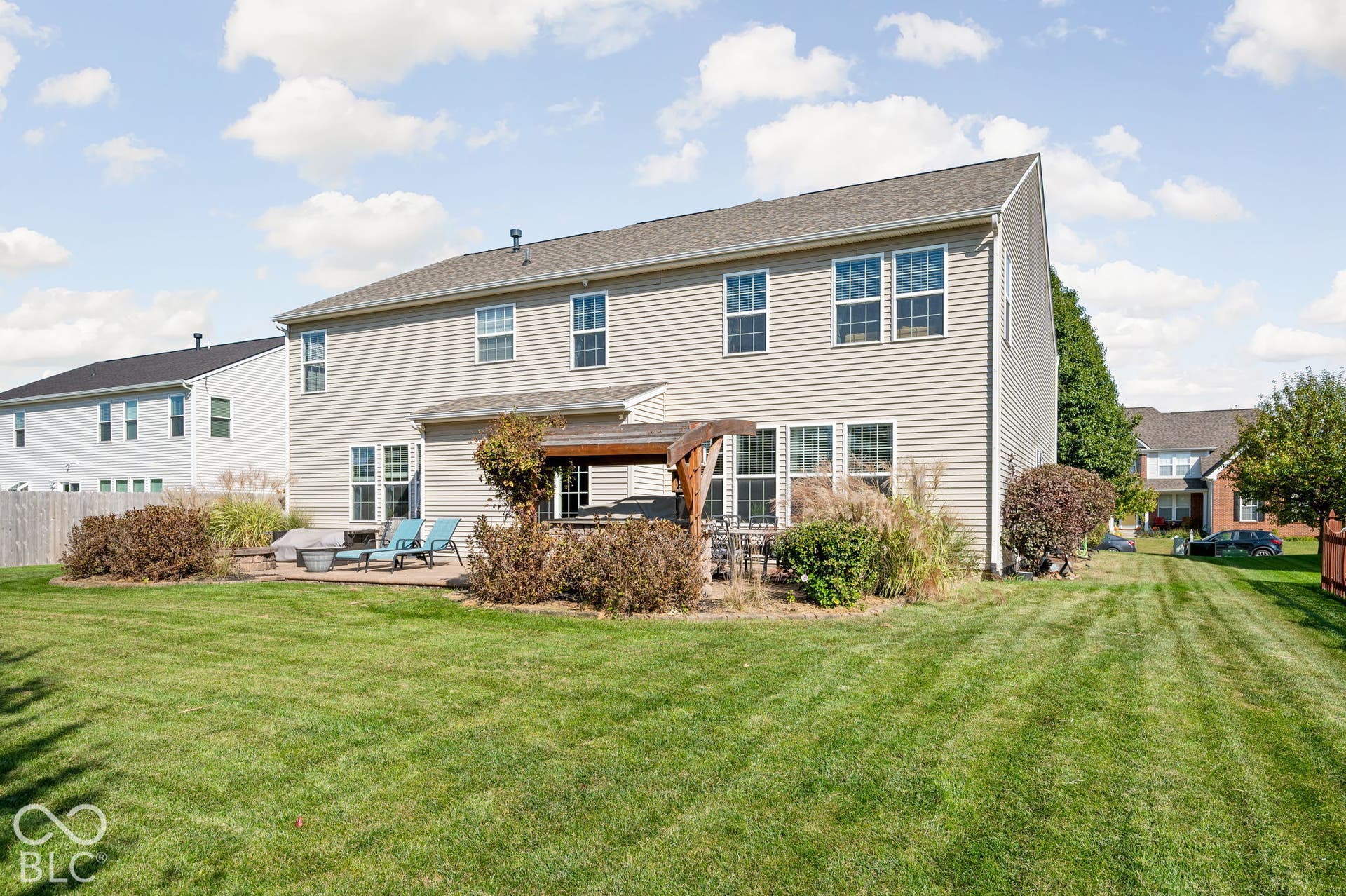 Expansive green lawn with a two-story residence featuring light-colored siding and a gabled roof